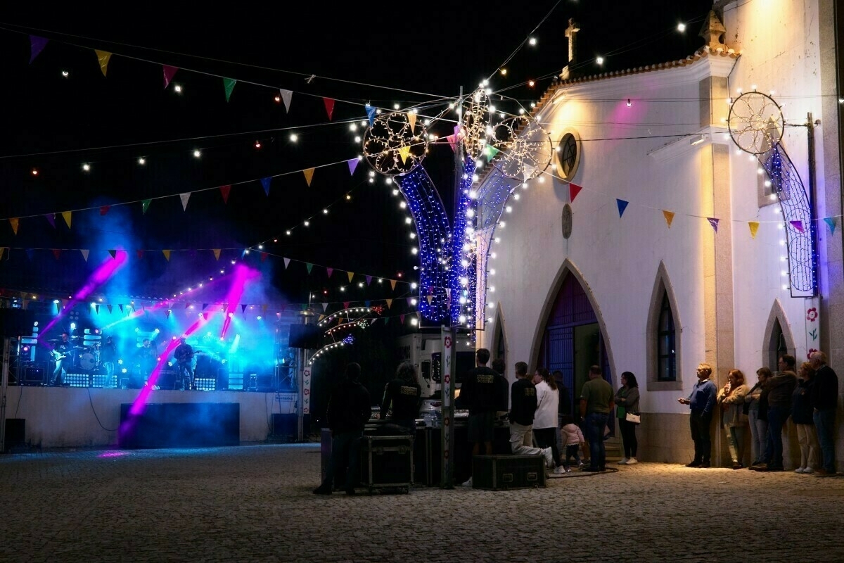 A vibrant nighttime festival scene features colorful lights, fog effects, and a crowd gathered near an illuminated building.