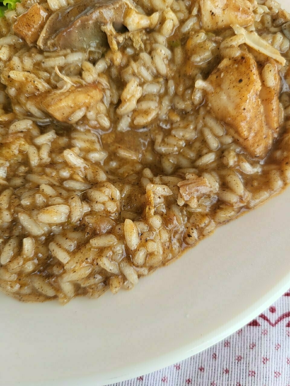 A plate of risotto with chunks of meat and a creamy, brown sauce.