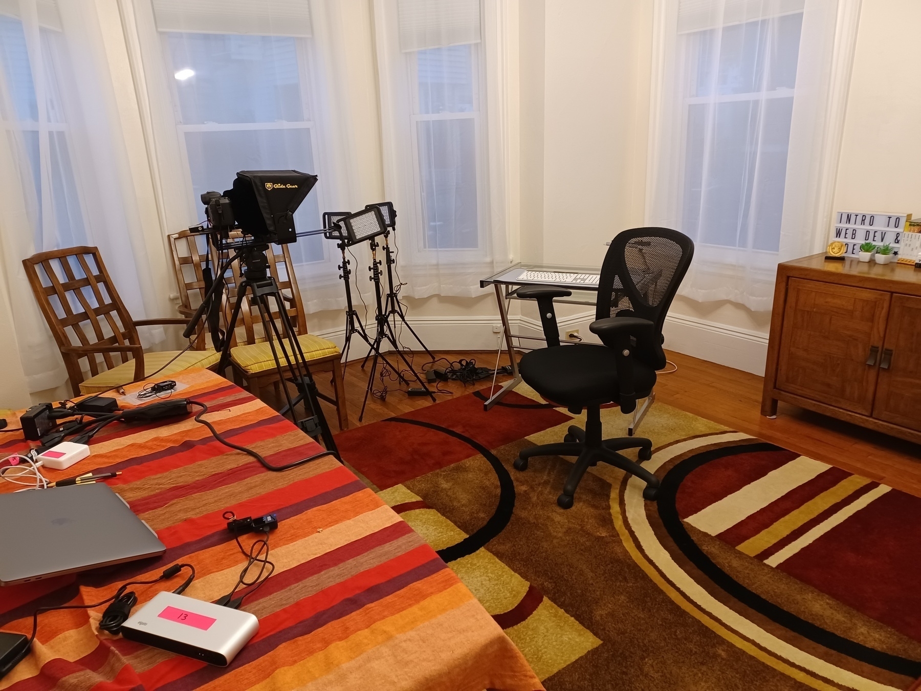 Dining room with teleprompter, recording computer, recording desk, and chair.