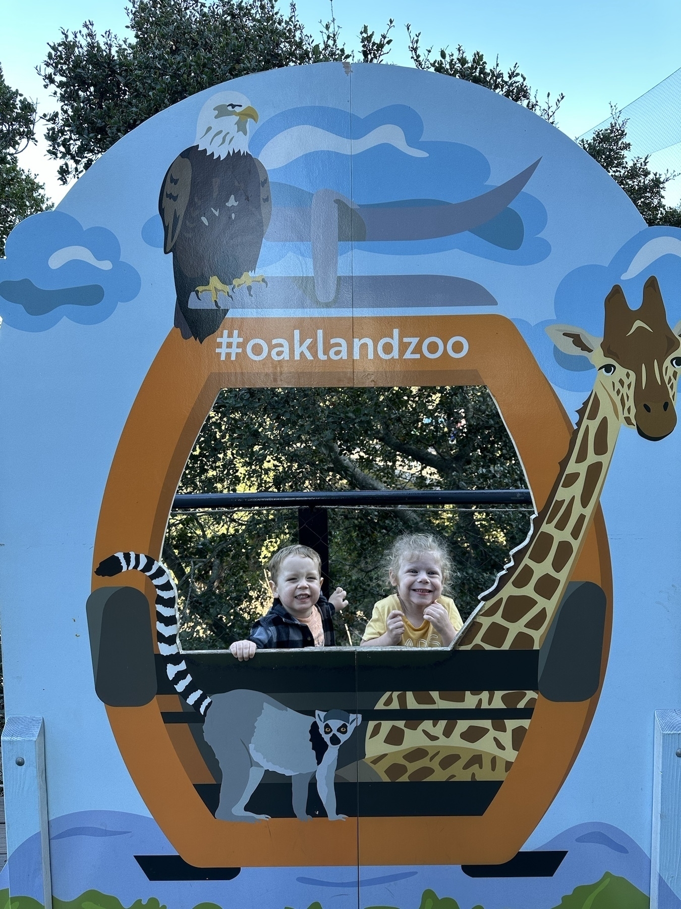 two children smiling behind a gondola sign