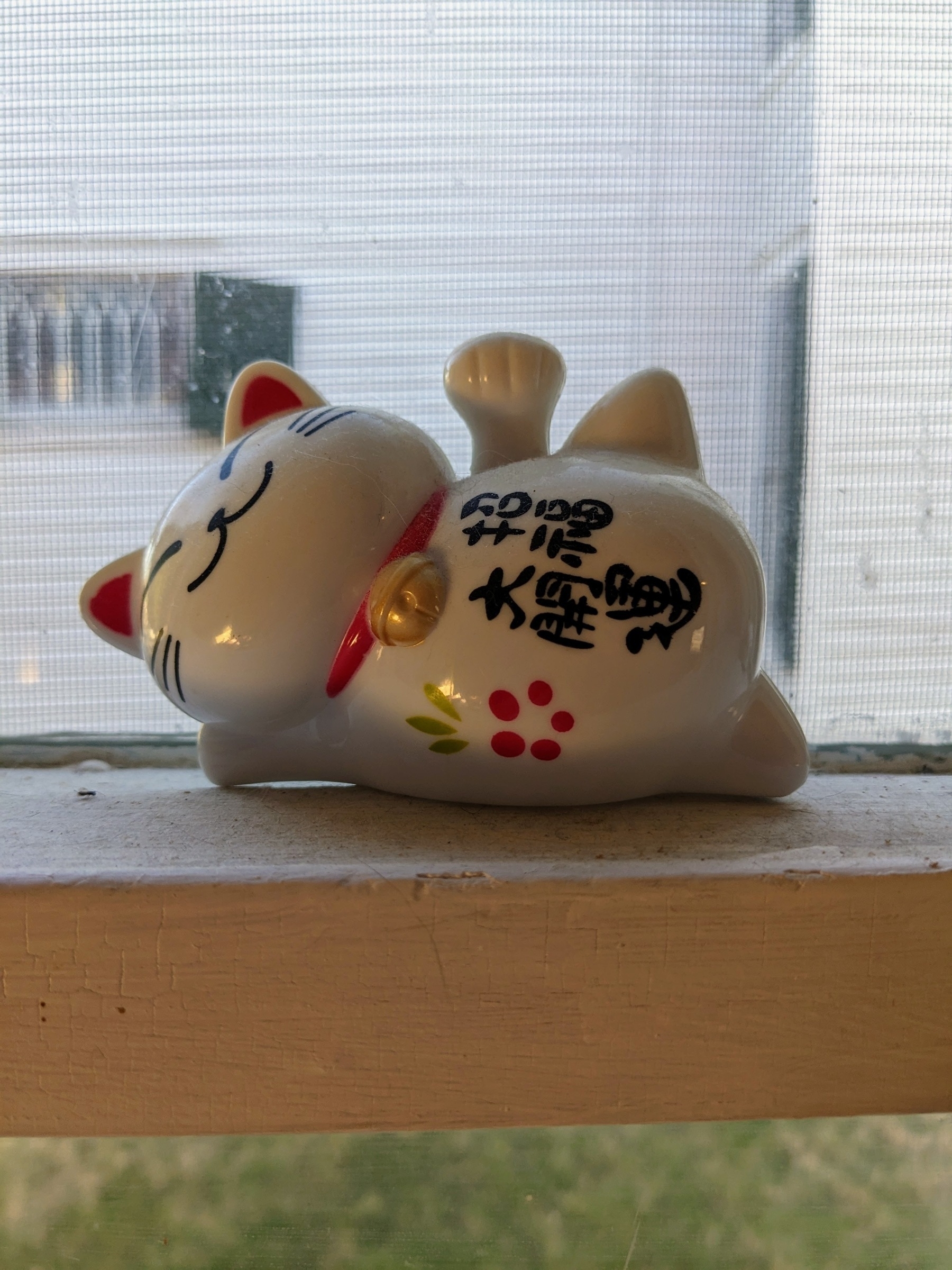plastic good luck maneki neko figurine on a windowsill