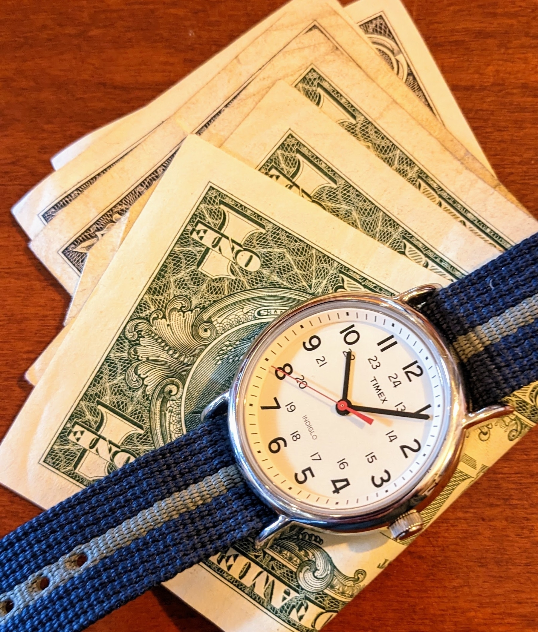 a Timex wristwatch lying on top of a couple of one dollar bills