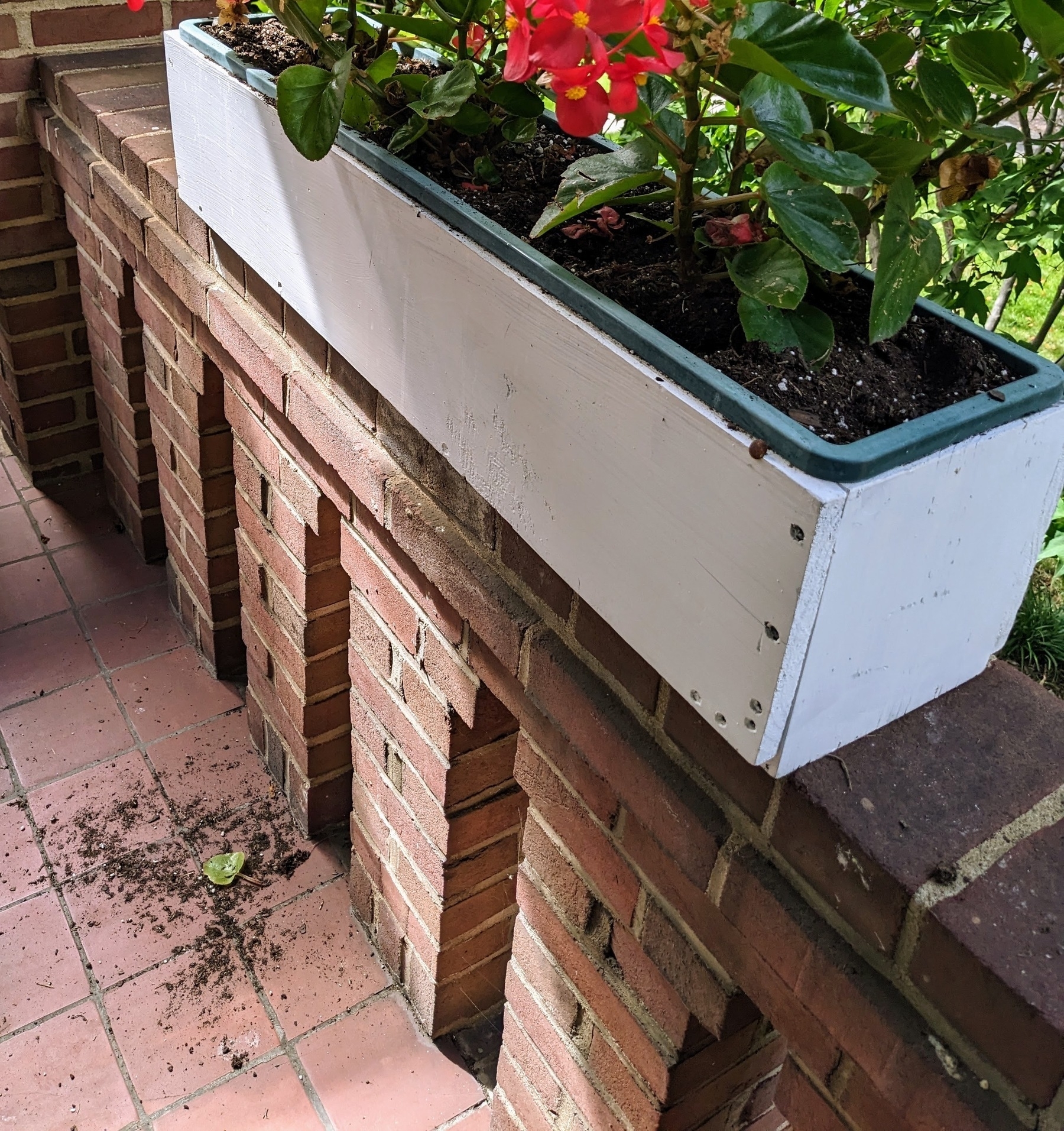 flower box on a porch with a pile of dirt on the ground