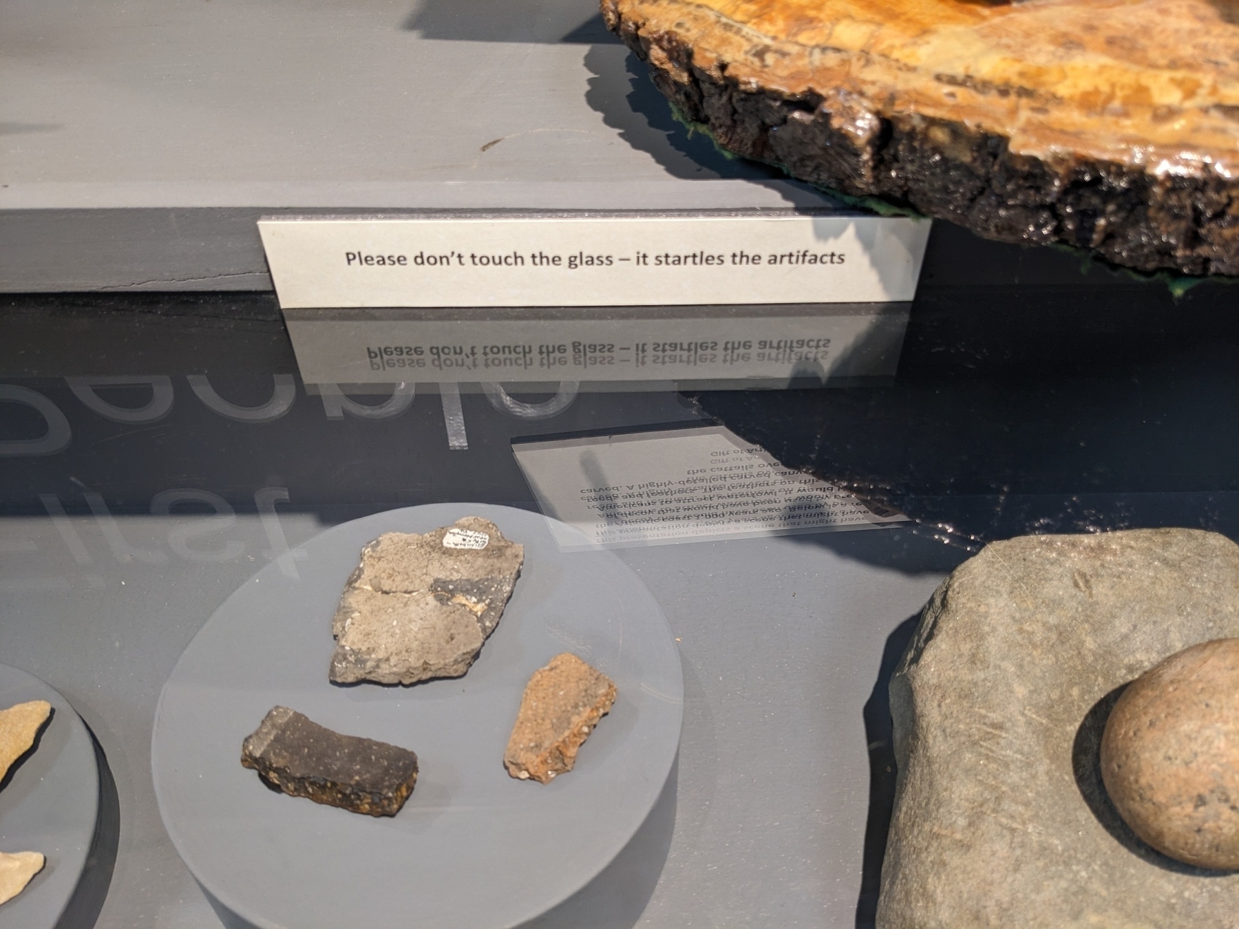 museum sign reading, 'please don't touch the glass, it startles the artifacts'