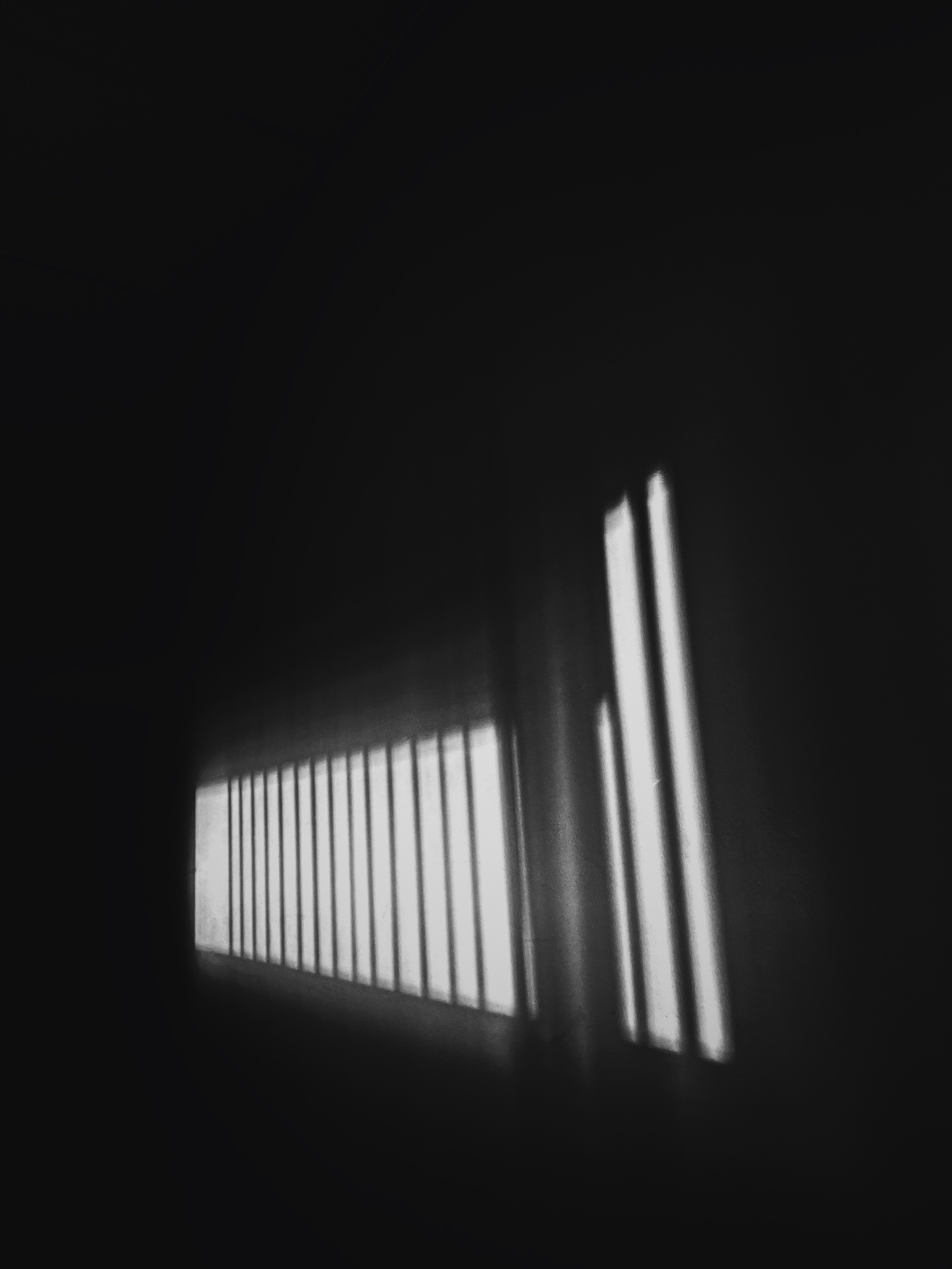 Photo: Capture inside my hallway with the early evening sun beaming through vertical blinds against the wall. The shot is black and white, with only the light visible and everything else darkened out.