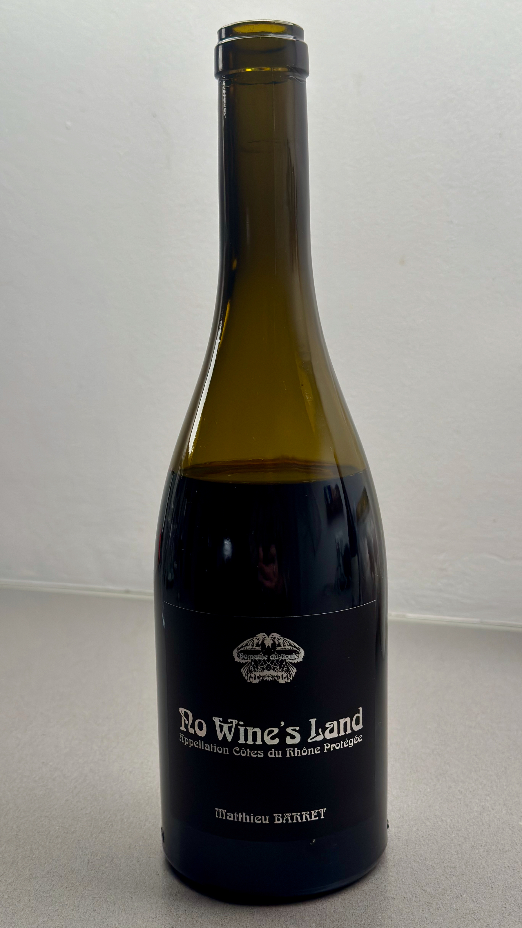 Auto-generated description: A bottle of wine labeled No Wine’s Land from the Côtes du Rhône region is shown against a neutral background.