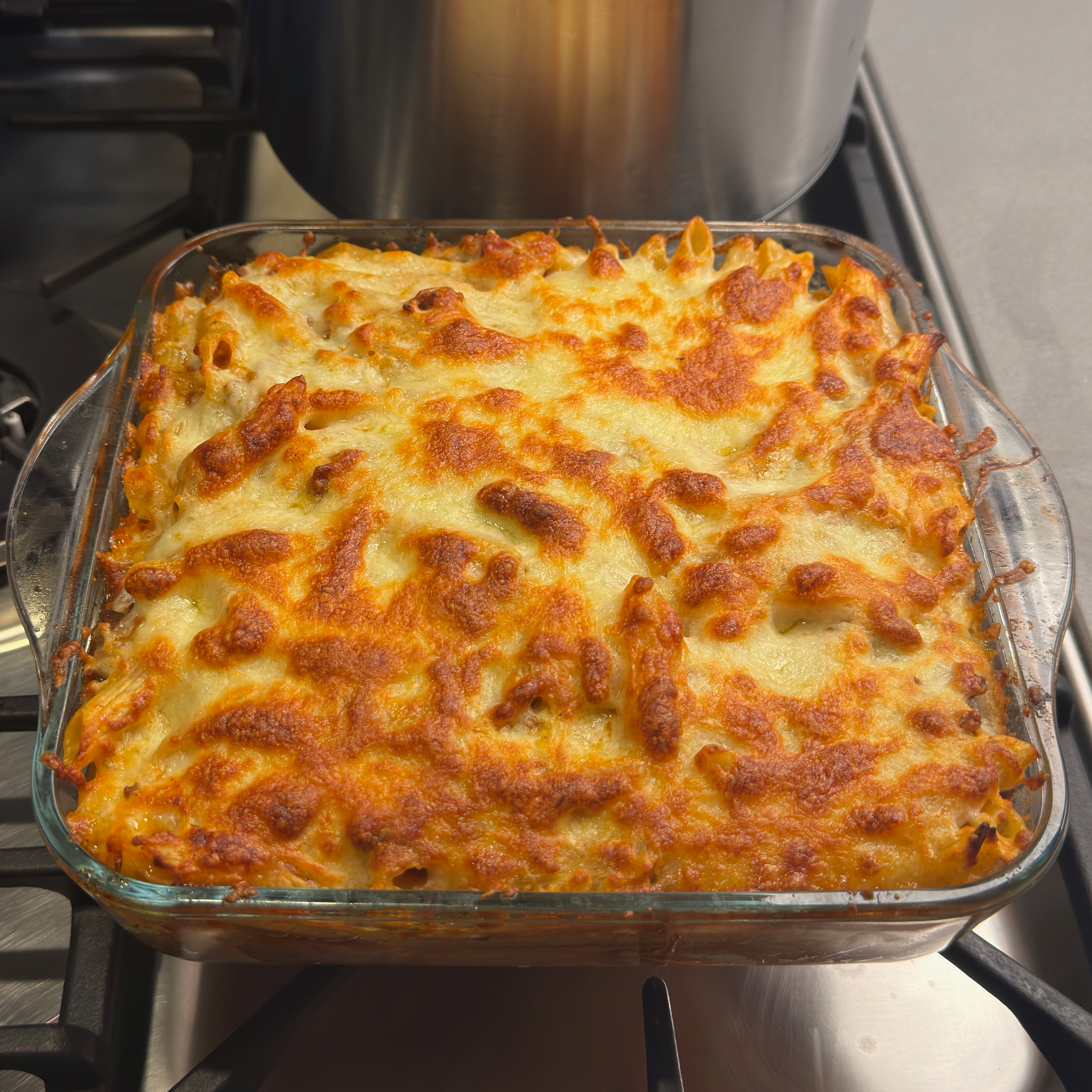 Auto-generated description: A baked pasta dish topped with golden, melted cheese sits on a stove.