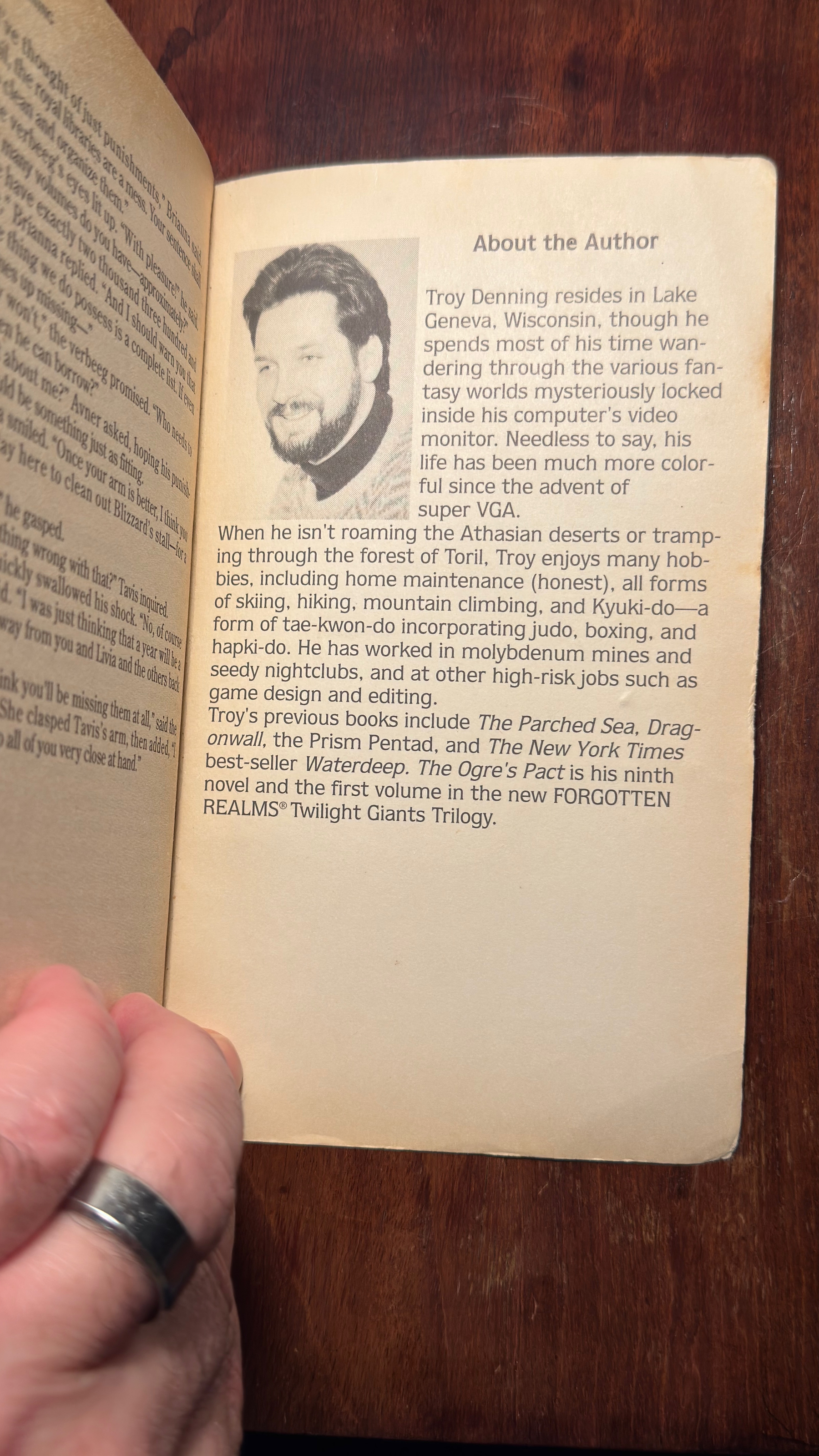 Auto-generated description: A person is holding open a book that displays a biographical section titled About the Author, featuring an image of an author with a beard.