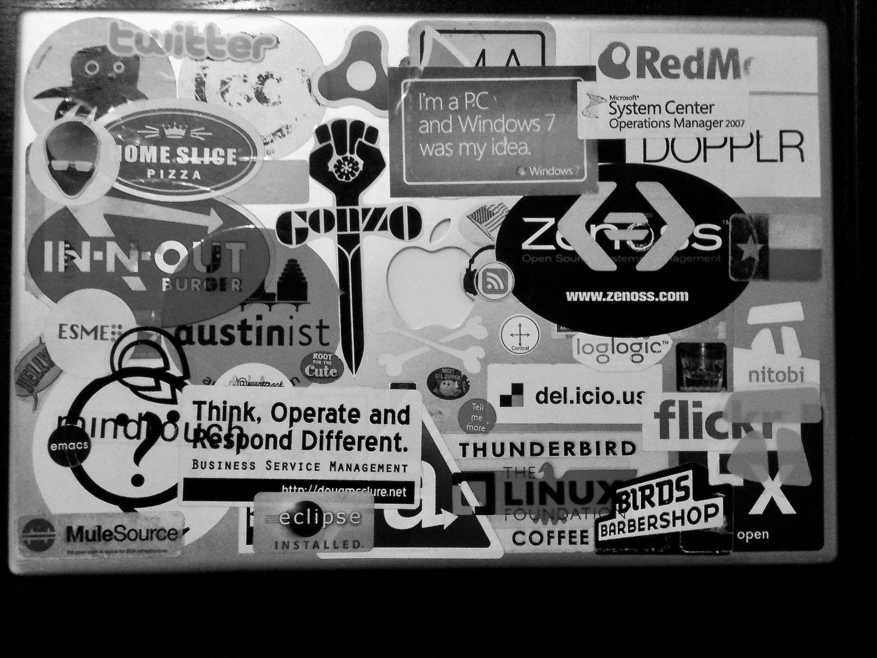 Auto-generated description: A collection of various tech and brand stickers is displayed on a surface, including logos for Twitter, In-N-Out Burger, and Apple.