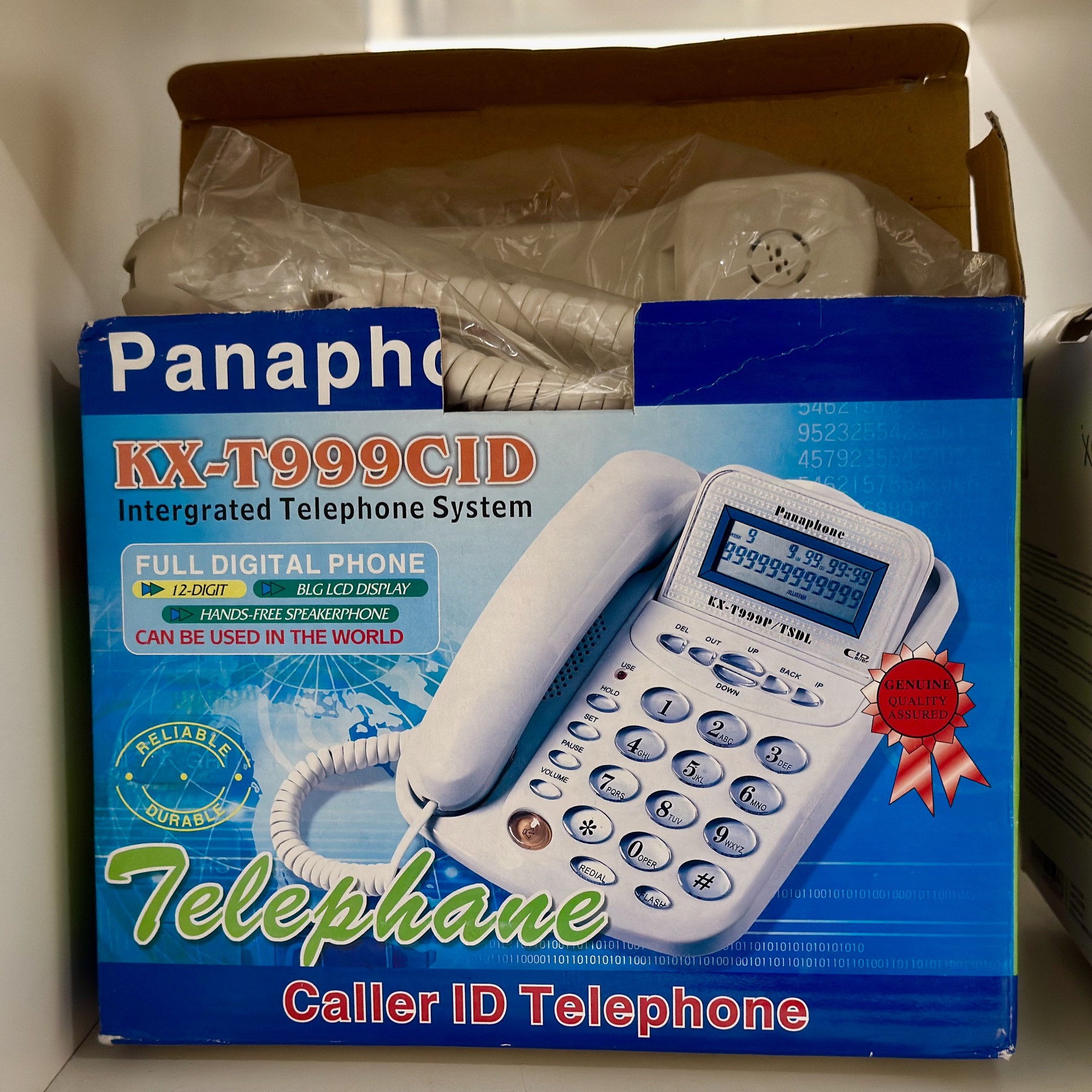 Auto-generated description: A boxed Panaphone KX-T999CID integrated telephone system with caller ID is displayed on a shelf.