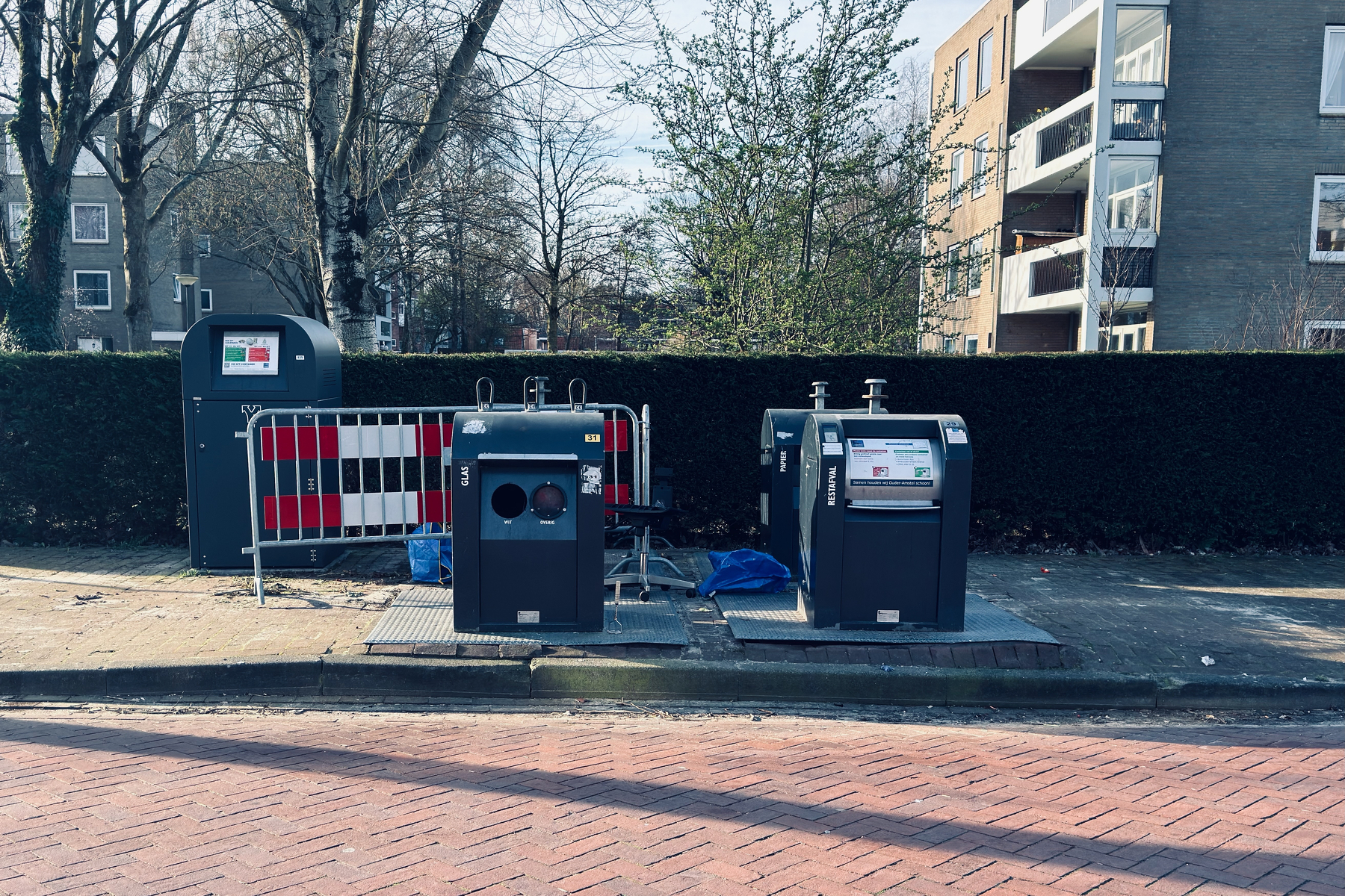 Underground waste containers on an Amsterdam street with an abandoned office chair wedged between them