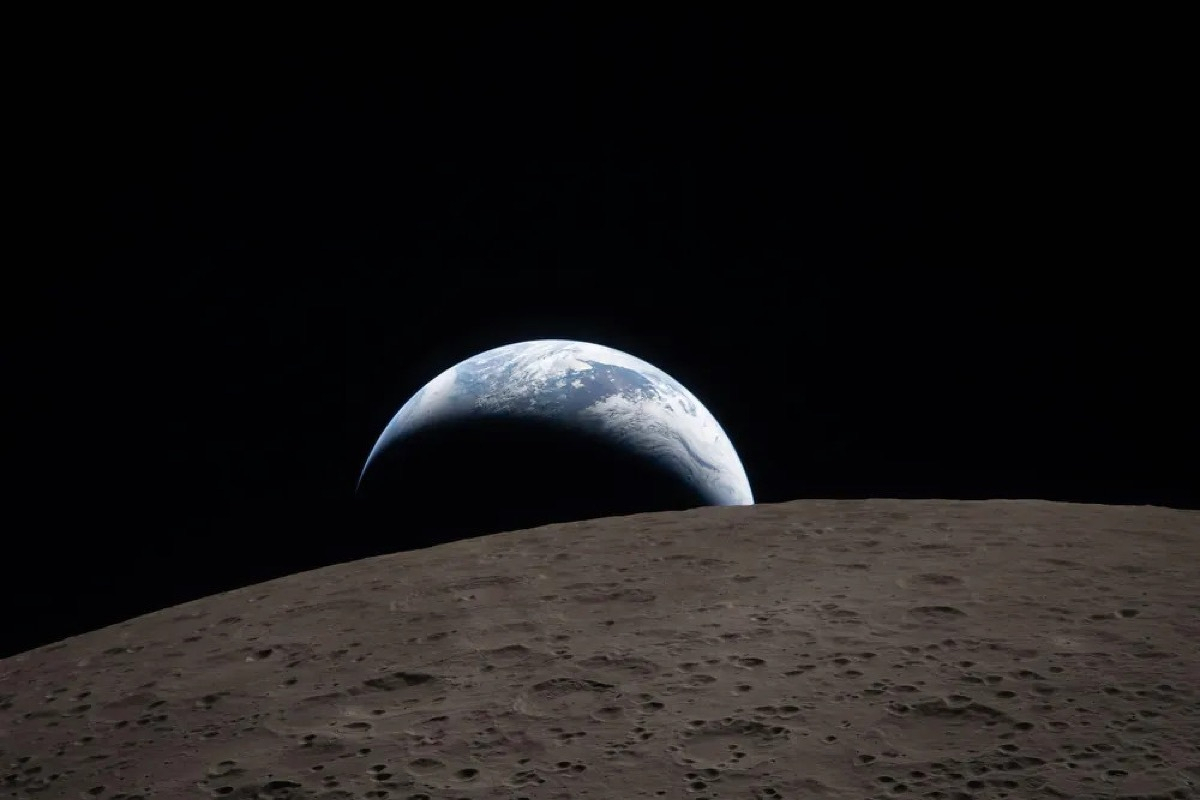 Earth rising over the lunar horizon, a crescent of blue and white against the blackness of space, with the grey cratered surface of the Moon in the foreground