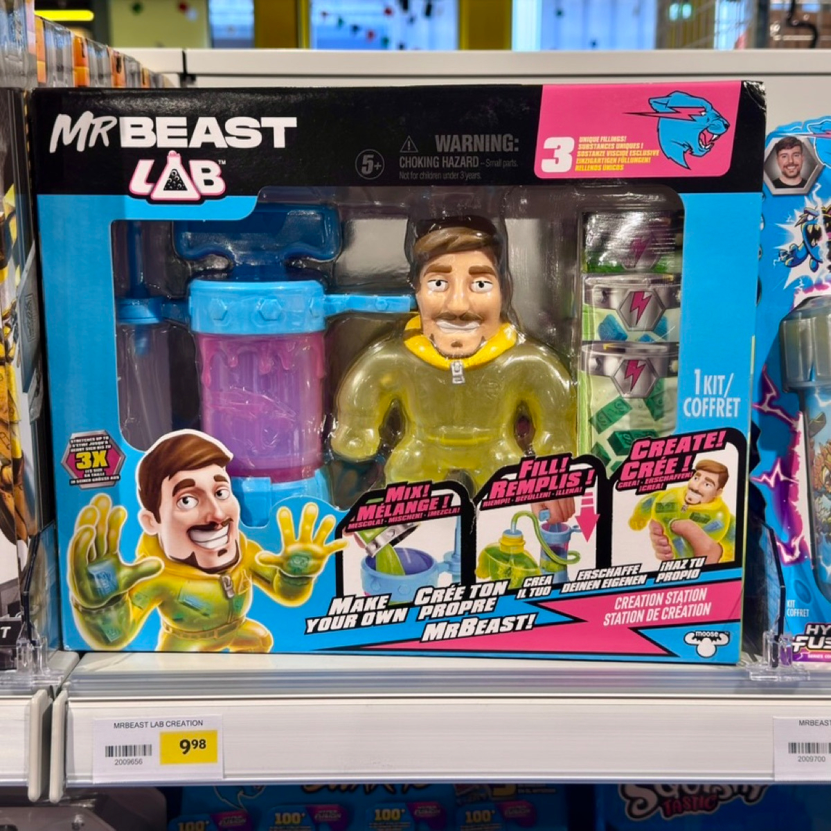Boxed 'MrBeast Lab Creation' toy on a store shelf, €9.98, featuring a yellow hazmat-suited MrBeast figure with mixing canisters and slime-fill ampoules.