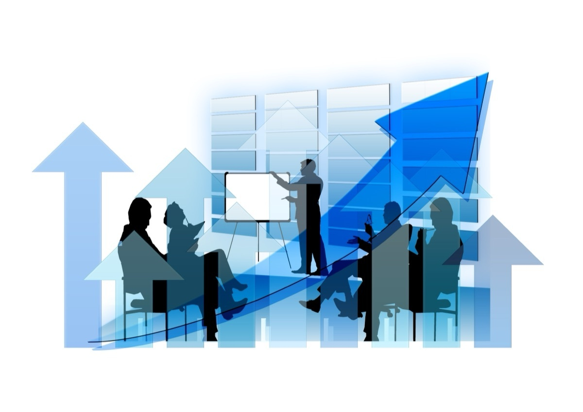 Silhouettes of business
  people seated around a presenter at a flip chart, set against a backdrop of blue upward arrows and a rising trend
  line.