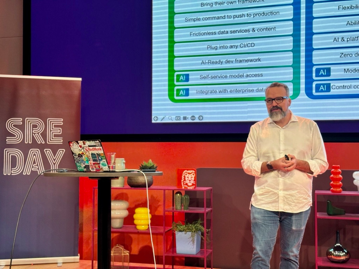 Coté on stage at SREDay Amsterdam in front of a slide listing platform capabilities including 'AI-Ready dev framework' and 'Self-service model access.'