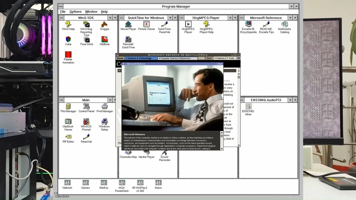 Windows 3.1 Program Manager running on a modern PC, showing open program groups including WinG SDK, QuickTime for Windows, and Microsoft Reference, with Microsoft Encarta 98 Encyclopedia displayed in the foreground. A modern RGB-lit PC tower is visible to the left of the monitor.