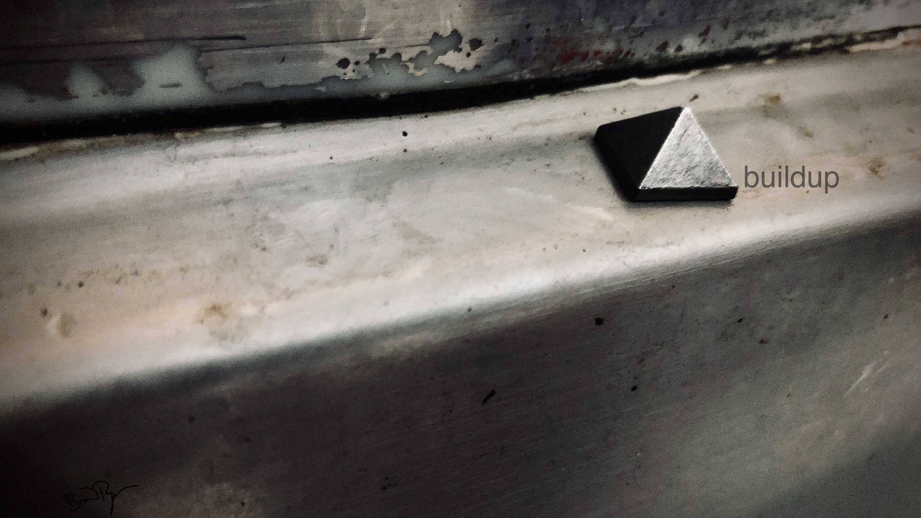 Close up of pyramid stud on metal shelf with corrosion and grime