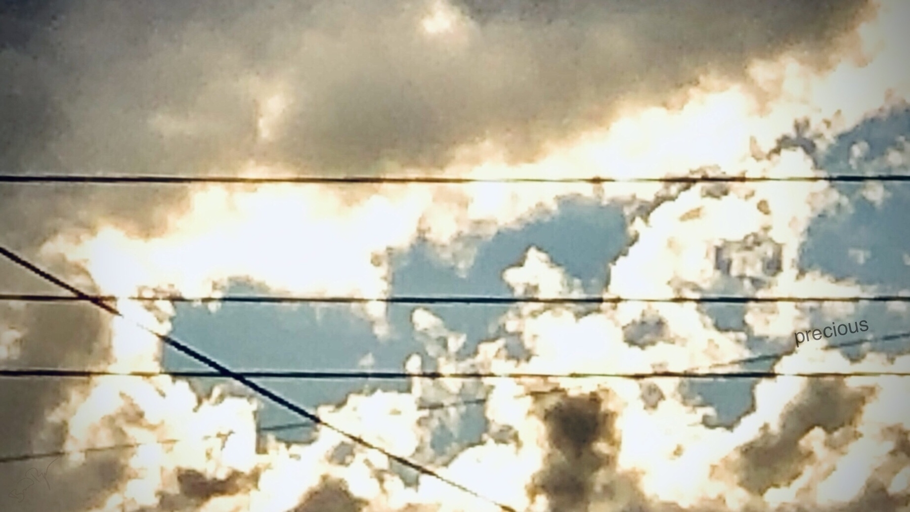 Dark clouds with sunshine lining and power lines criss-crossing. The question is which is more precious, the sun or the powergrid? 
