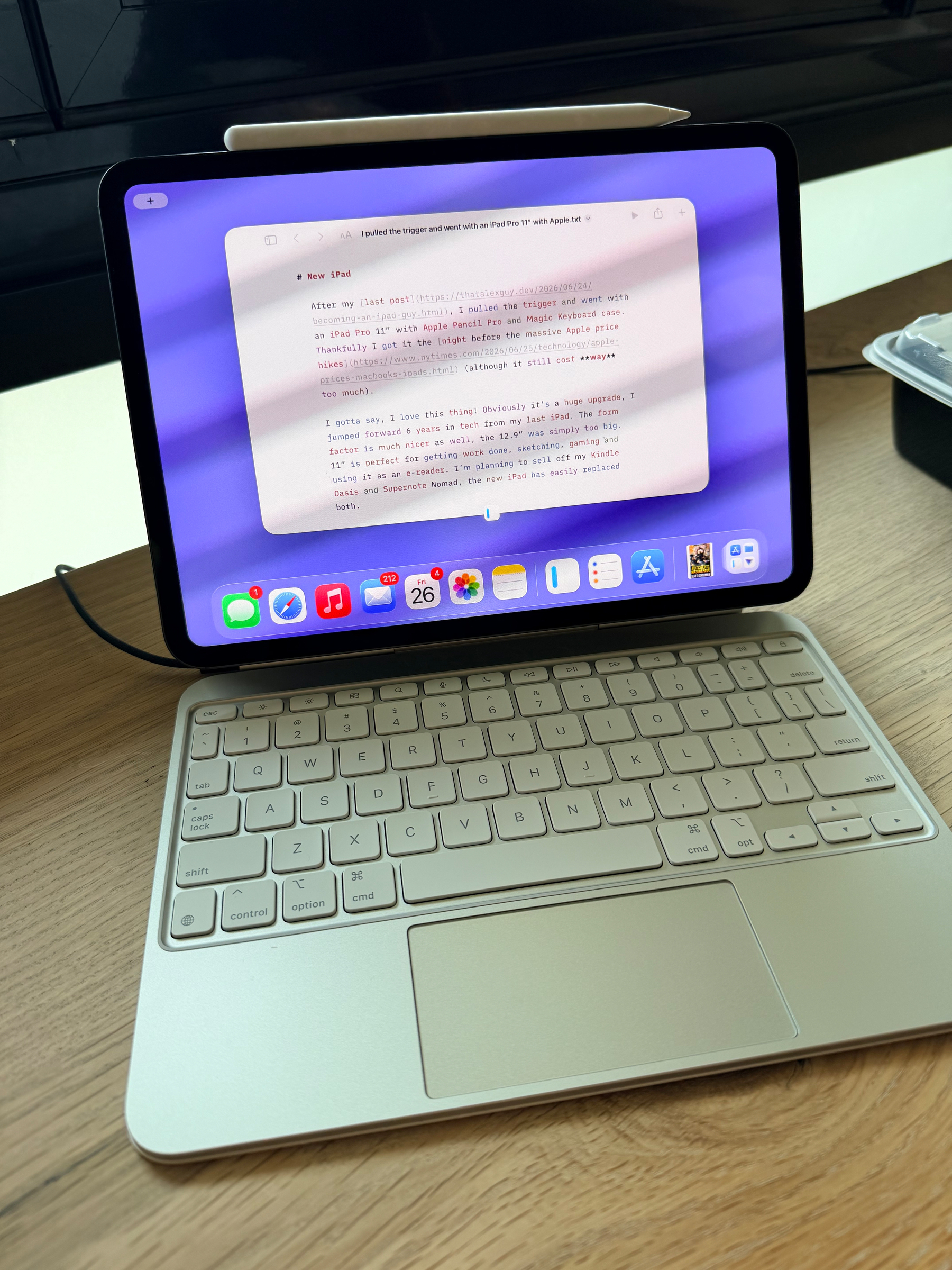 A tablet with an attached keyboard and a stylus on top is placed on a wooden surface displaying a note-taking app with typed text.