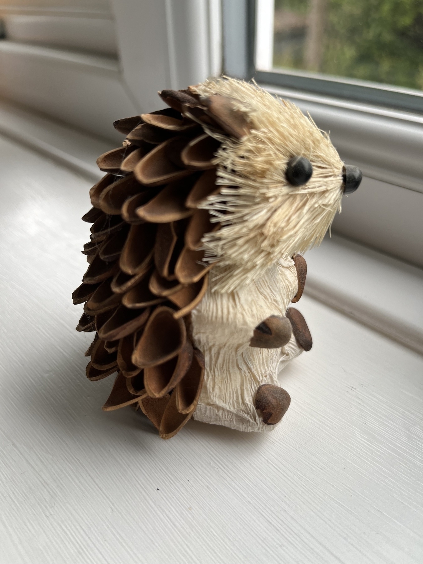 An ornamental hedgehog, with spines made out of halved nut shells, and fur made out of dried grass. 