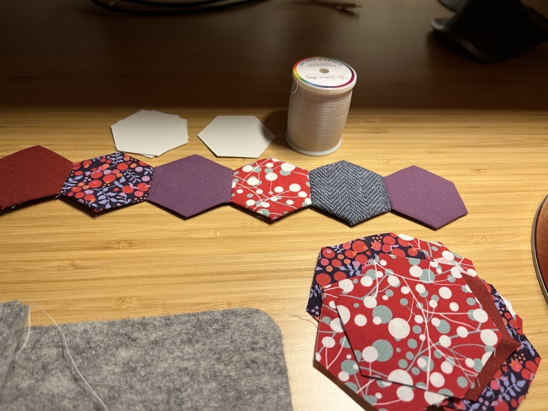 A row of fabric hexagons sewn together in shades of red, purple and blue. 