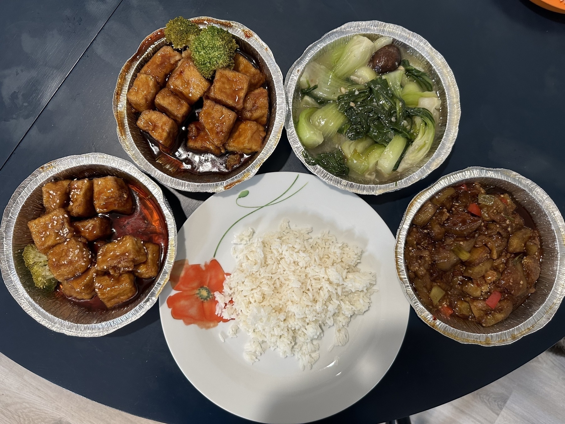 General Tso's tofu, sesame tofu, garlic bok choy, and garlic eggplant with a plate of steamed rice.