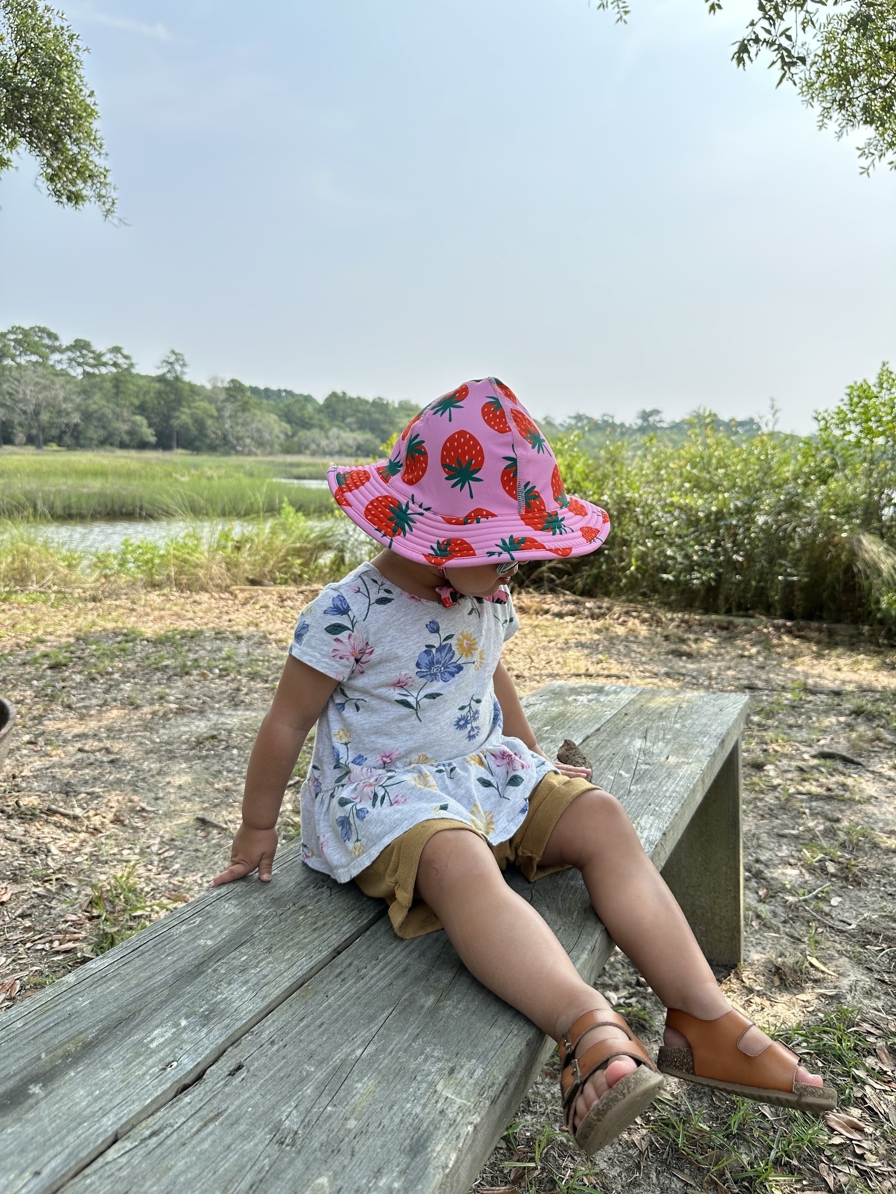 my daughter sitting on a bench at Magnolia Plantation overlooking the Ashley River