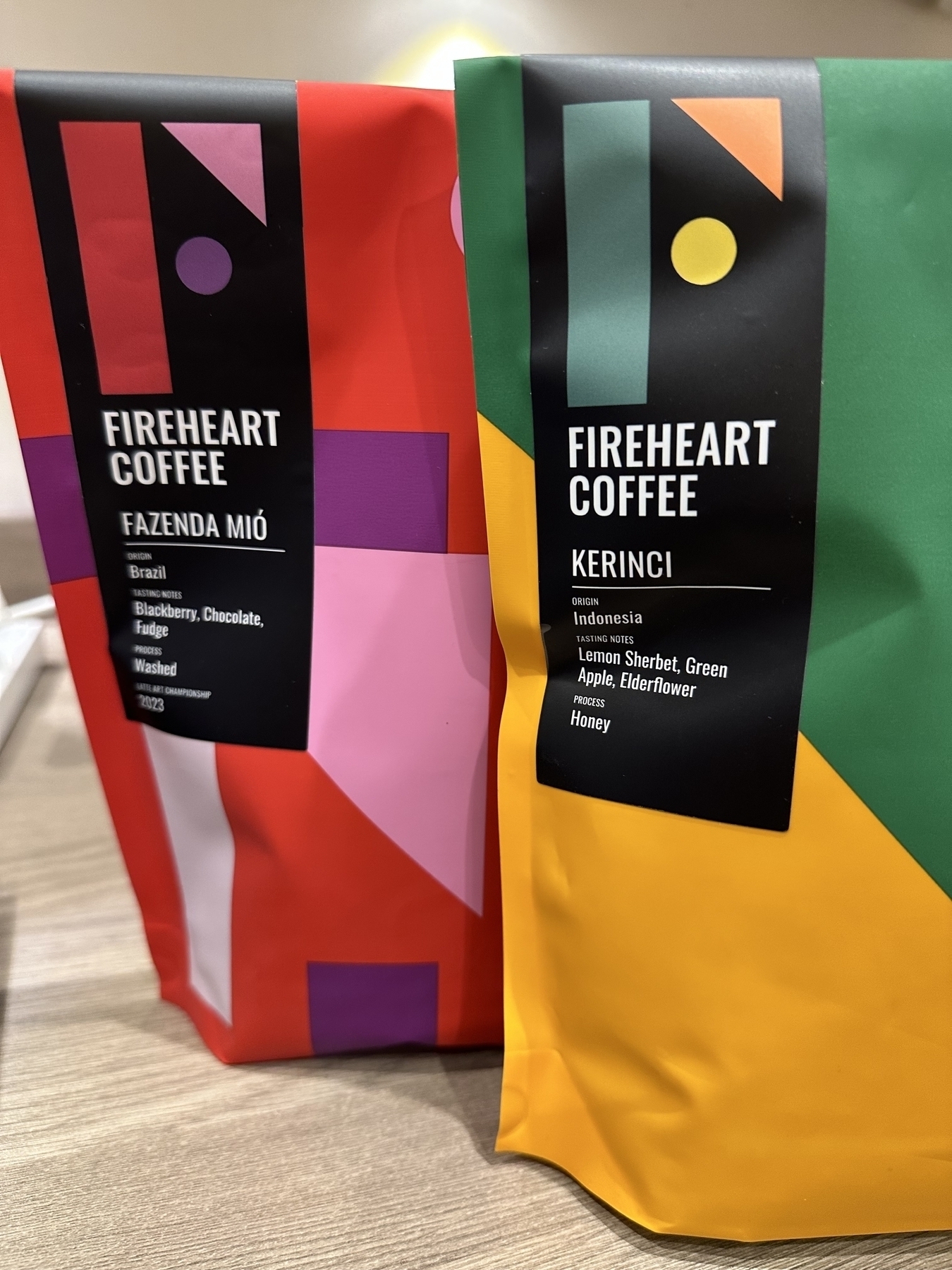 Two bags of coffee from Fireheart Coffee, one red bag of Brazil and one green bag from Indonesia.