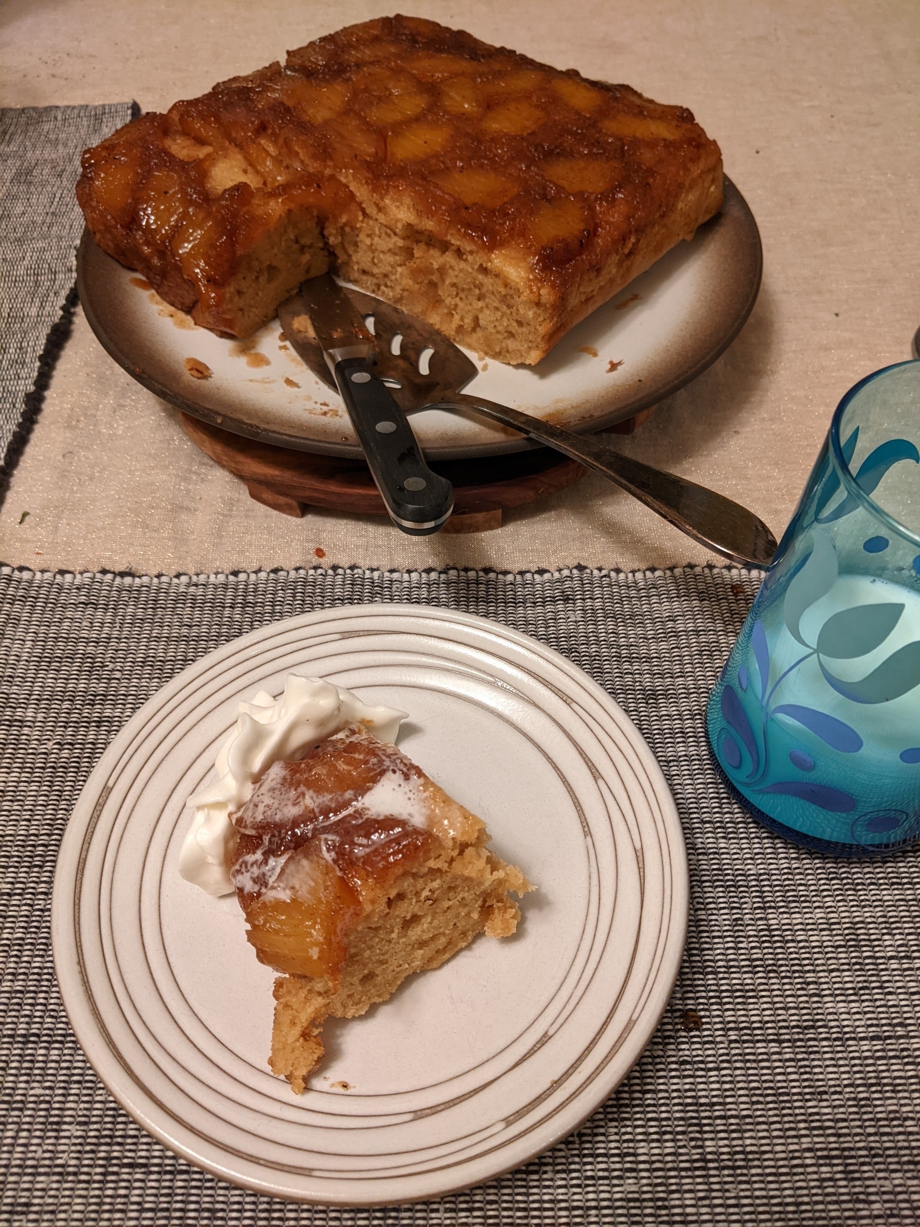 slice of cake with whipped cream next to plate of pineapple upside down cake 