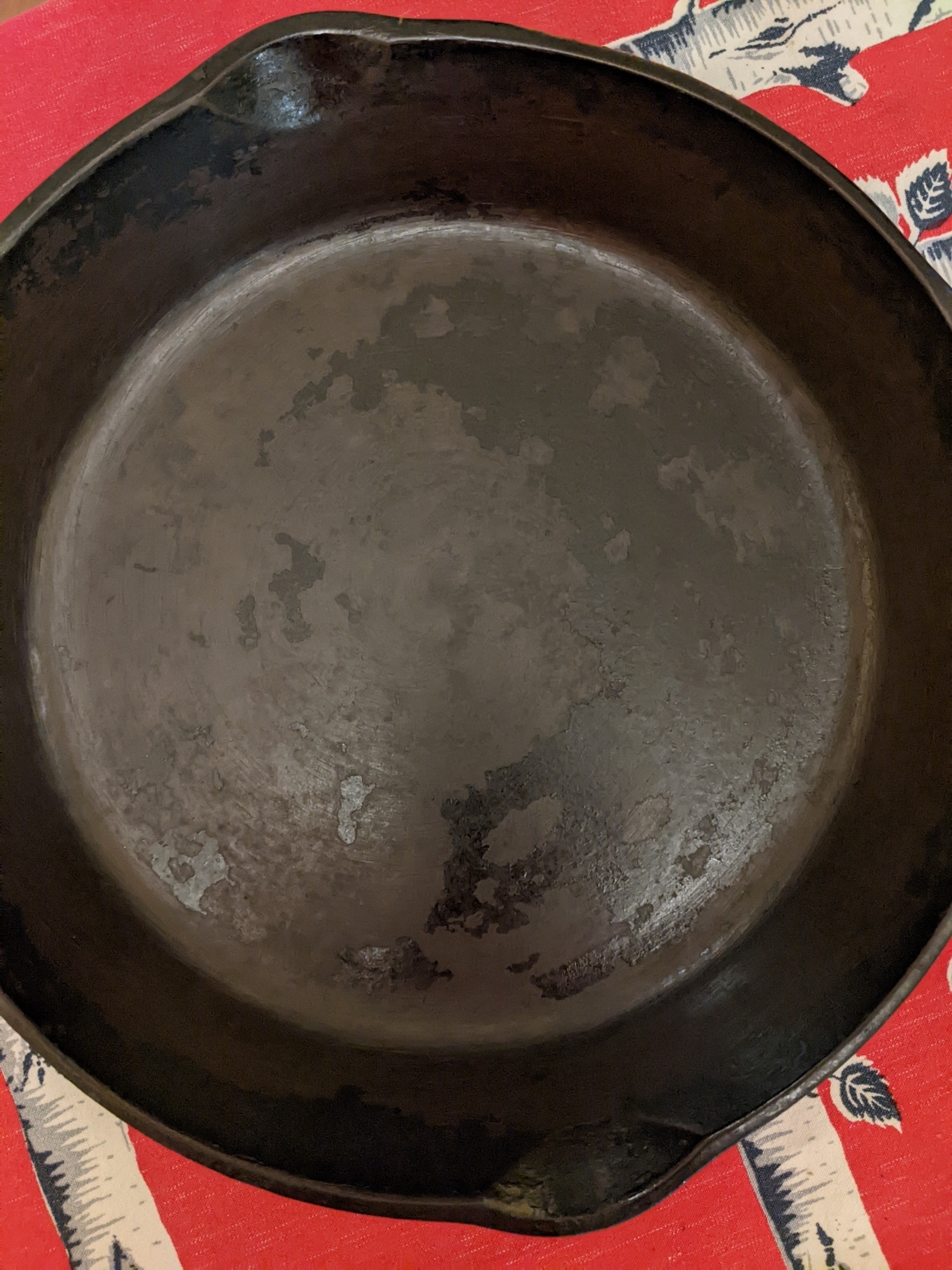 Cast iron pan with two coats of oil, looking darker but still patchy 