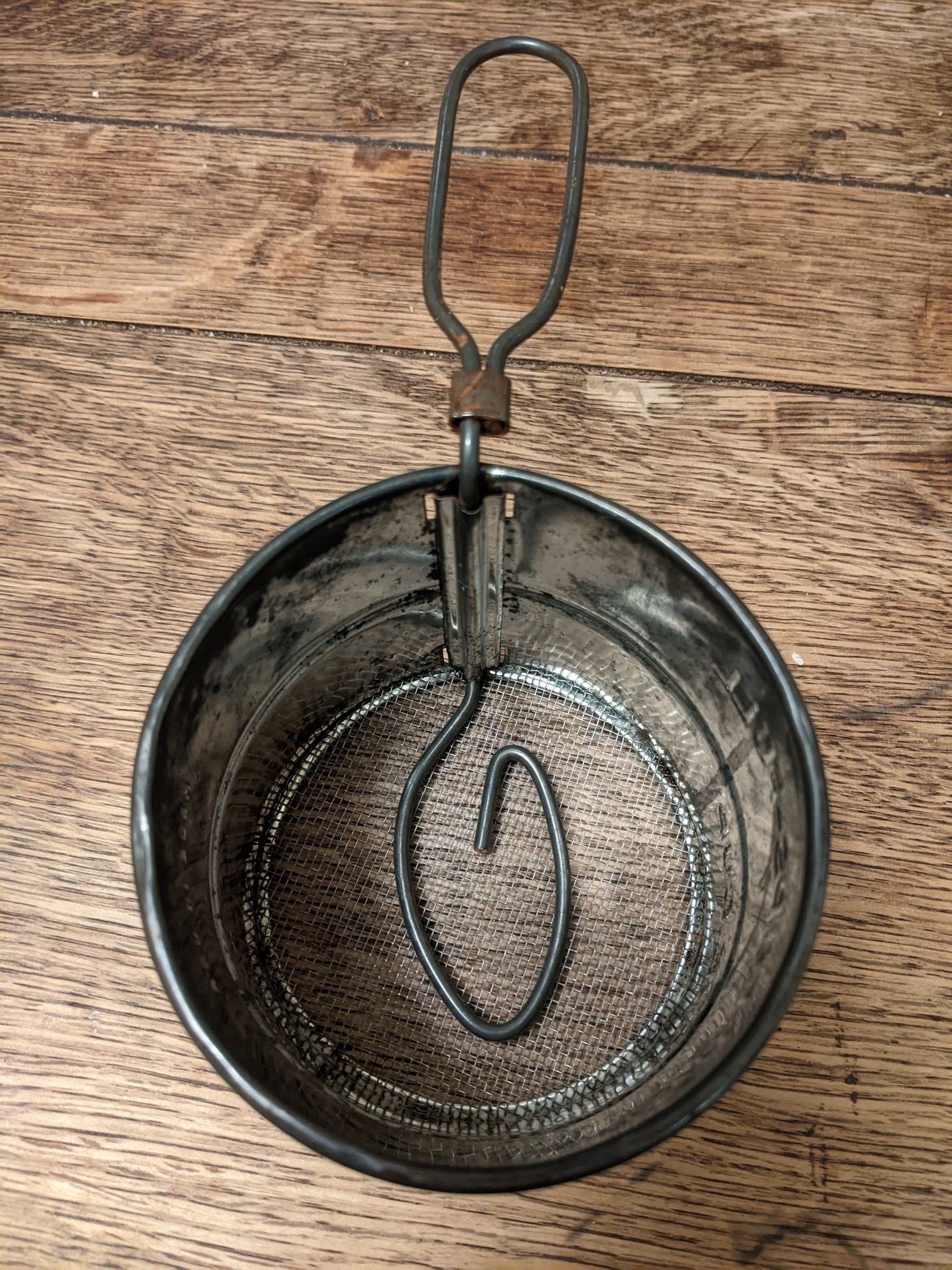 looking down at vintage tin sifter with curved metal wire along the screen 