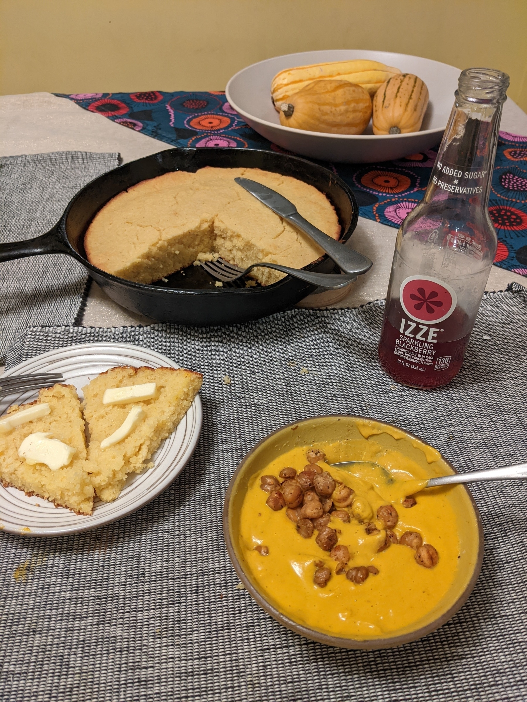 Squash soup topped with crispy chickpeas, split slice of cornbread with butter, Izze blackberry drink and a cast iron skillet of cornbread 