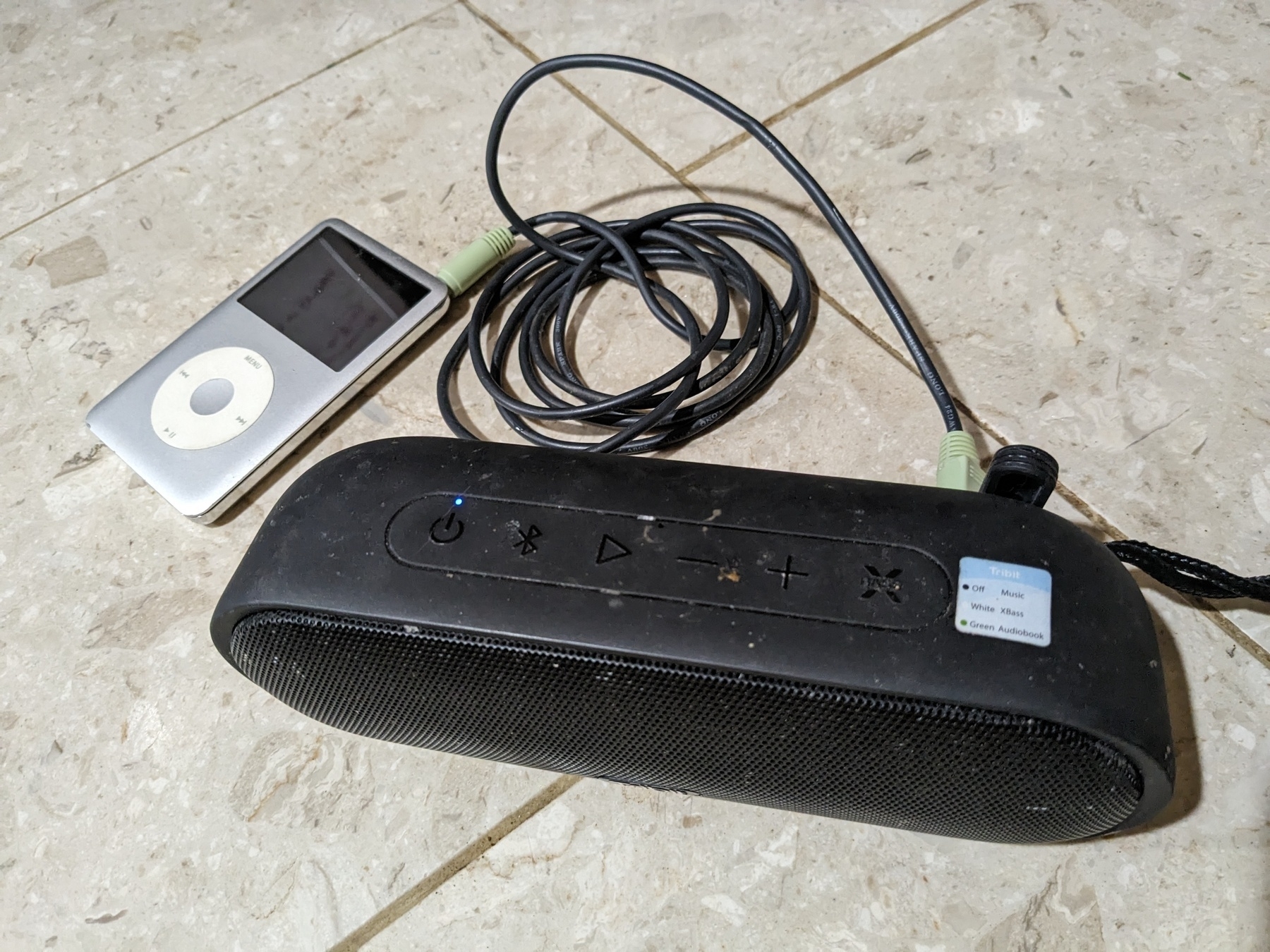 silver iPod connected to Bluetooth speakers with an aux cord