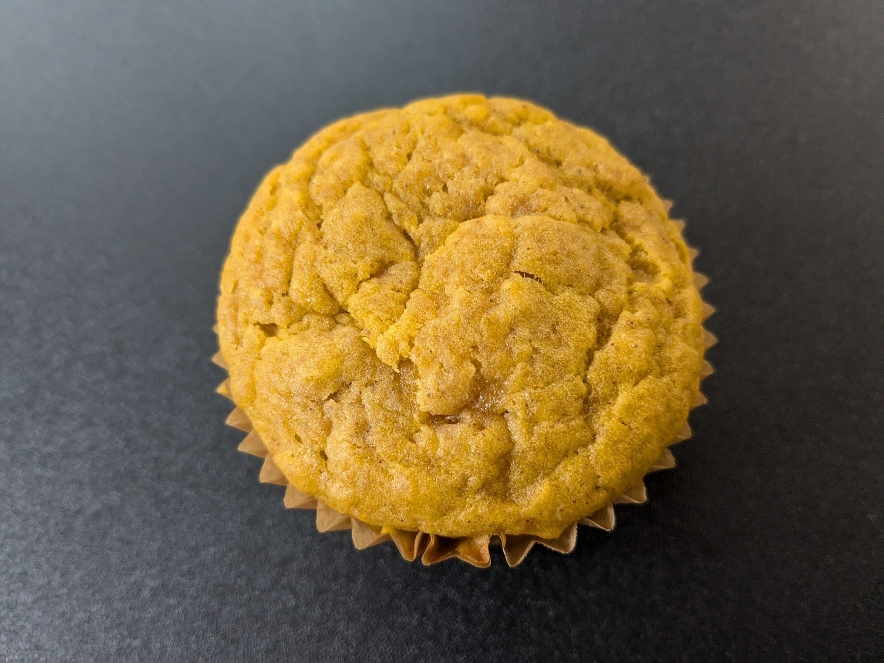 single warm orange pumpkin muffin on a black background 