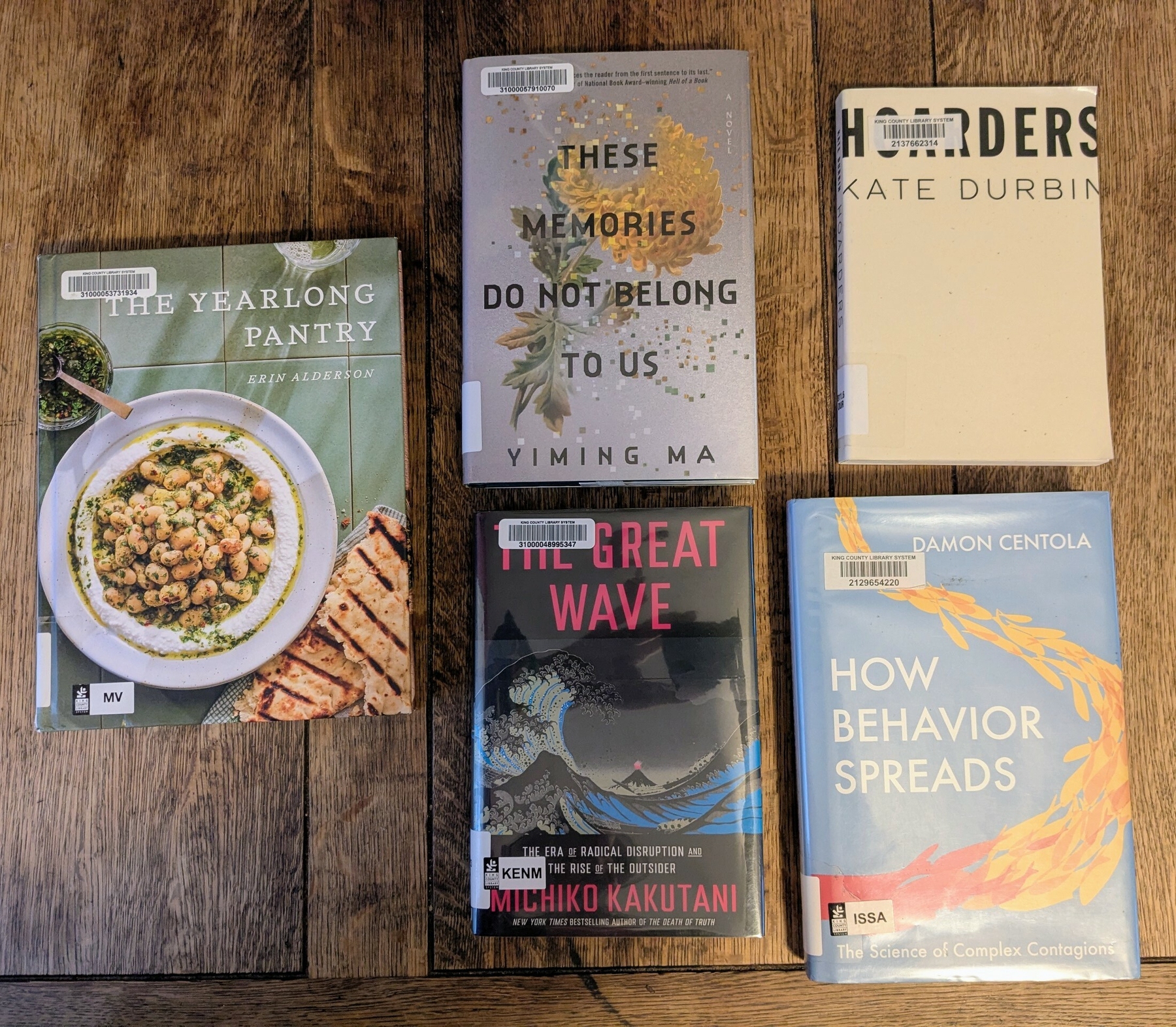 flatlay of a cookbook, novel, prose poem collection, and two nonfiction library books