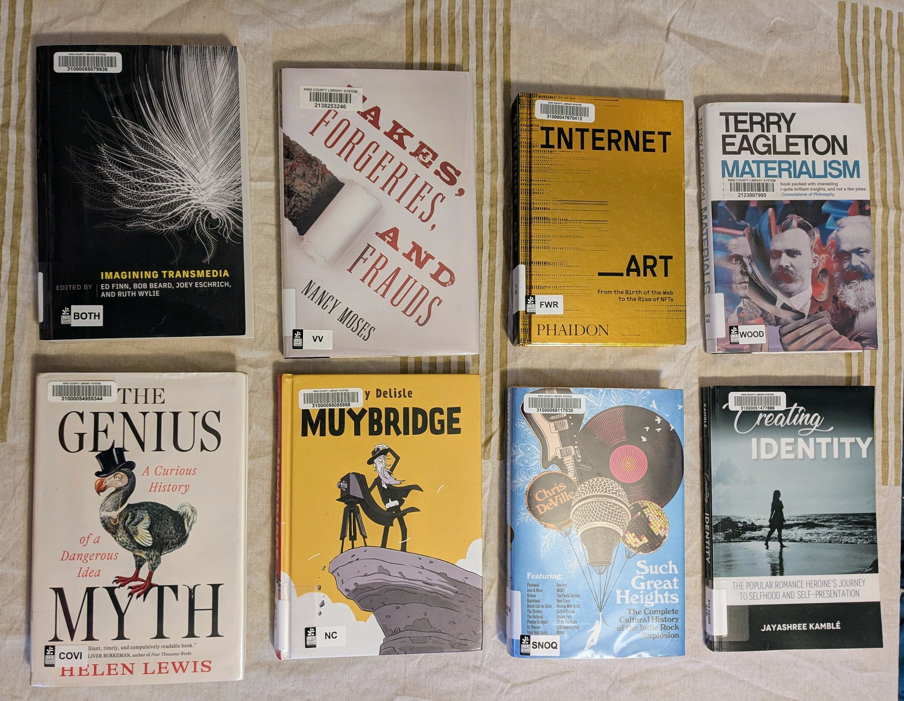 flatlay of 8 nonfiction library books, including one anthology, one Phaidon art book, and one graphic biography 