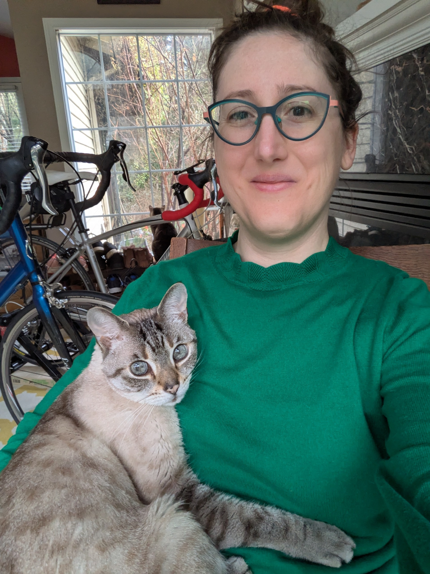 woman sitting in rocking chair with cat tucked in one arm, paw across the woman's chest like a hug