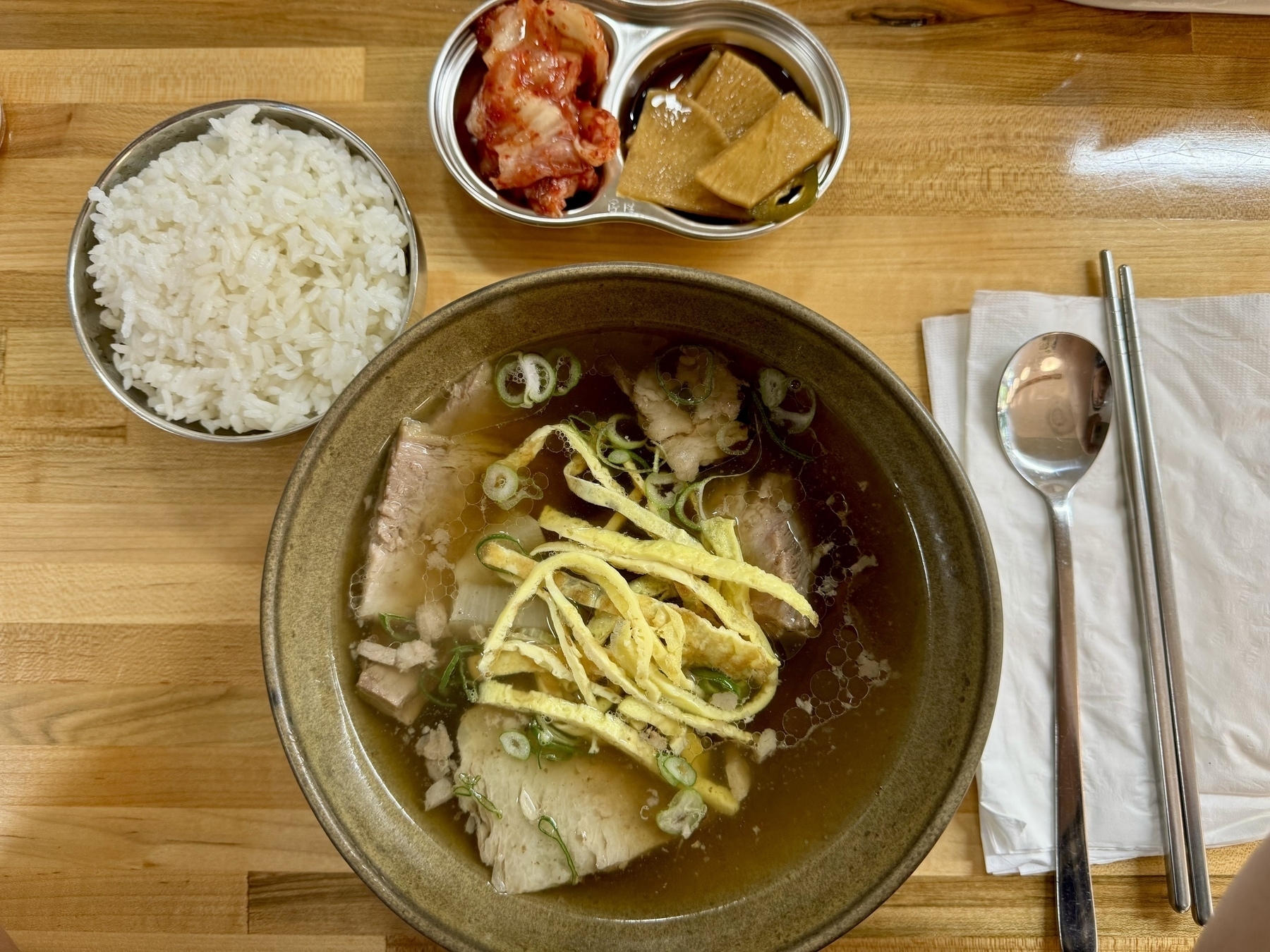 A top down picture of a bowl of galbi tang (short rib soup), rice, and kimchi. &10;