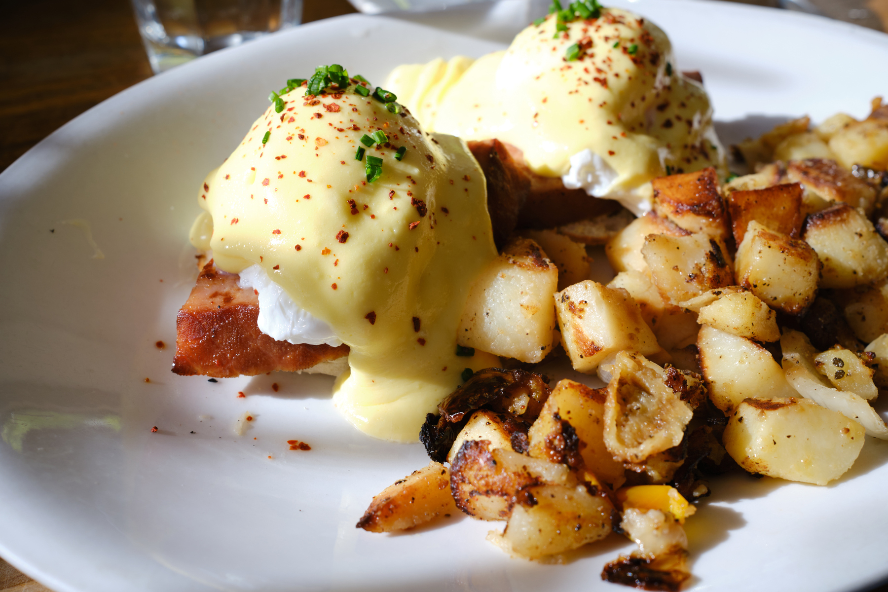 Eggs benedict, served with an extra thick slice of smoked ham and a side of breakfast potatoes.