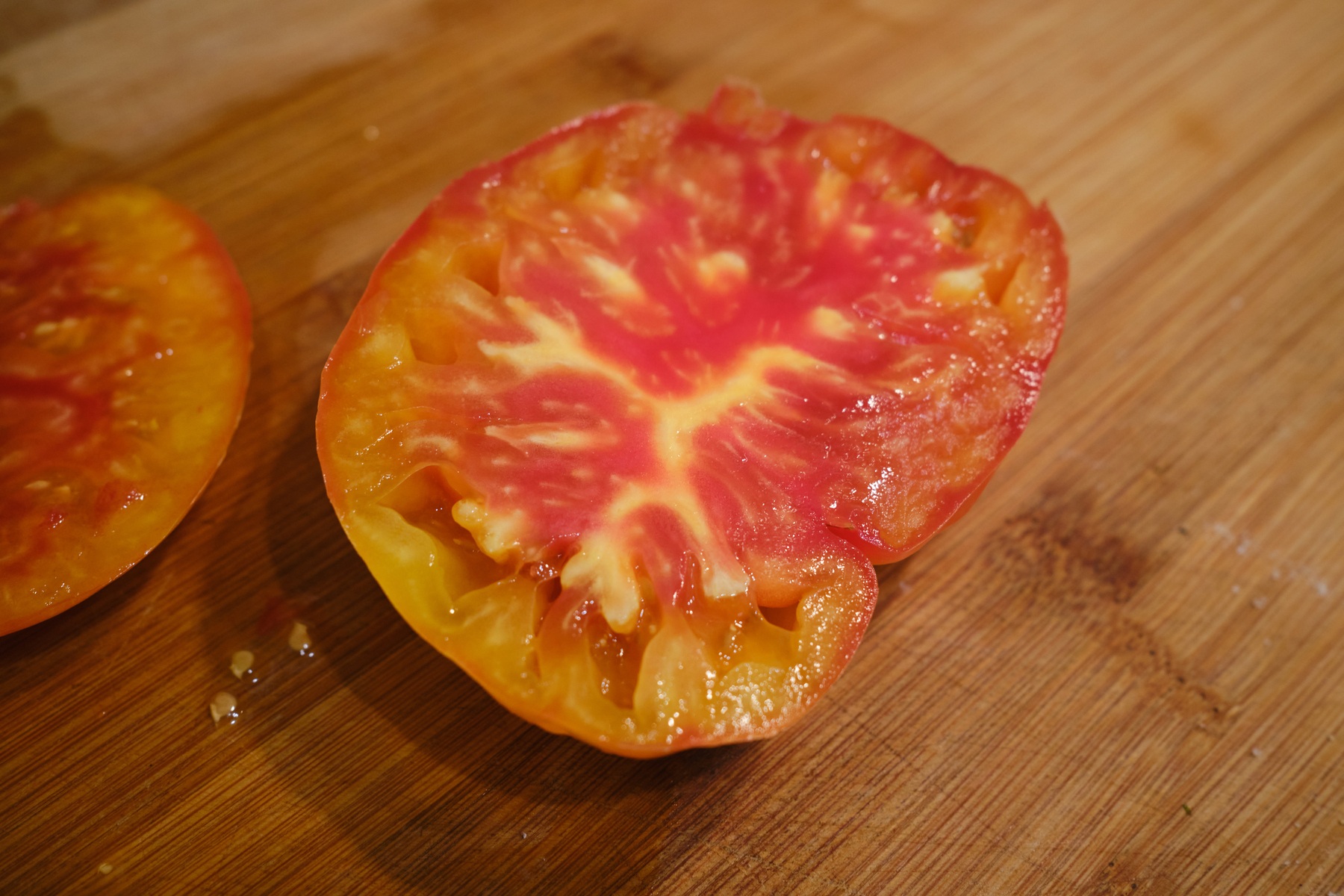 A half of a heirloom tomato, showing streaks of reds and yellows. 