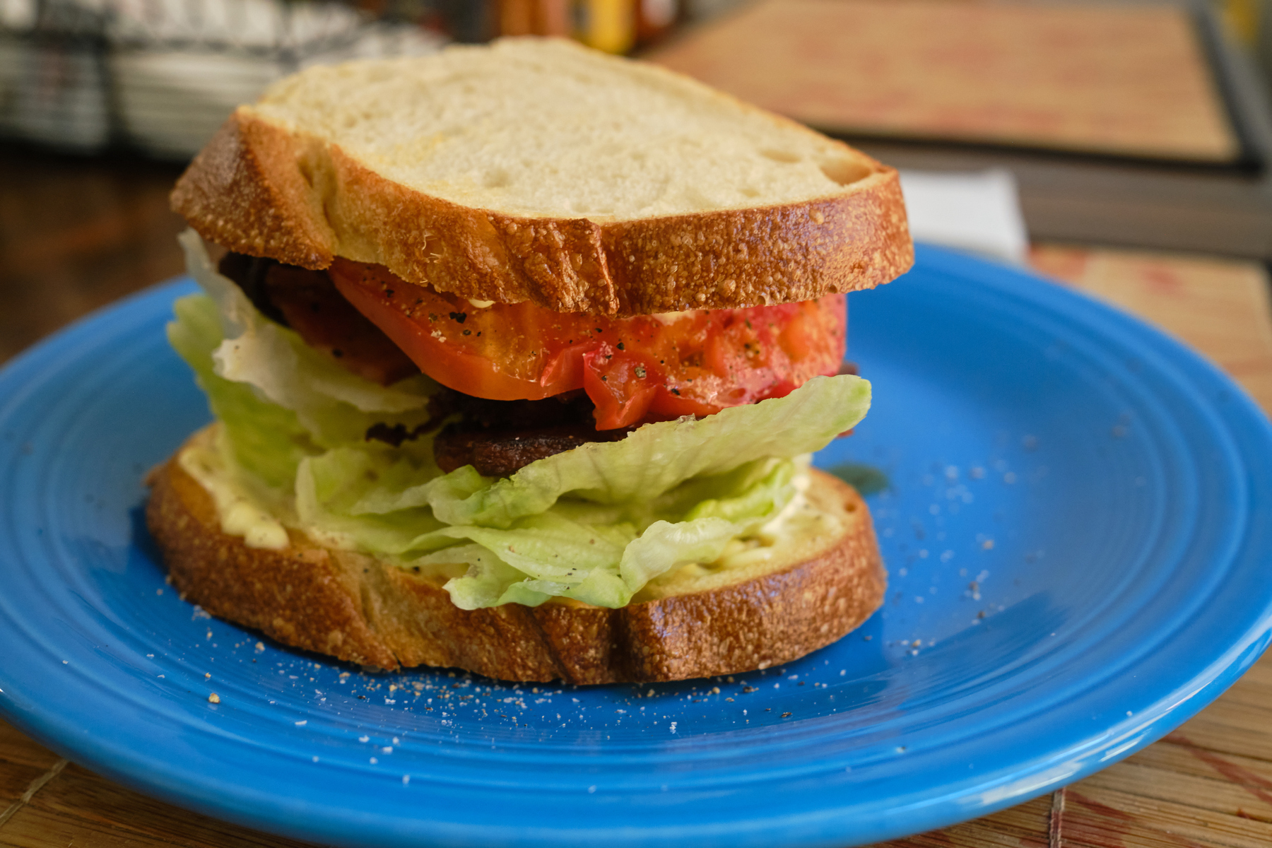 A bacon, lettuce, and tomato sandwich on a blue plate. 
