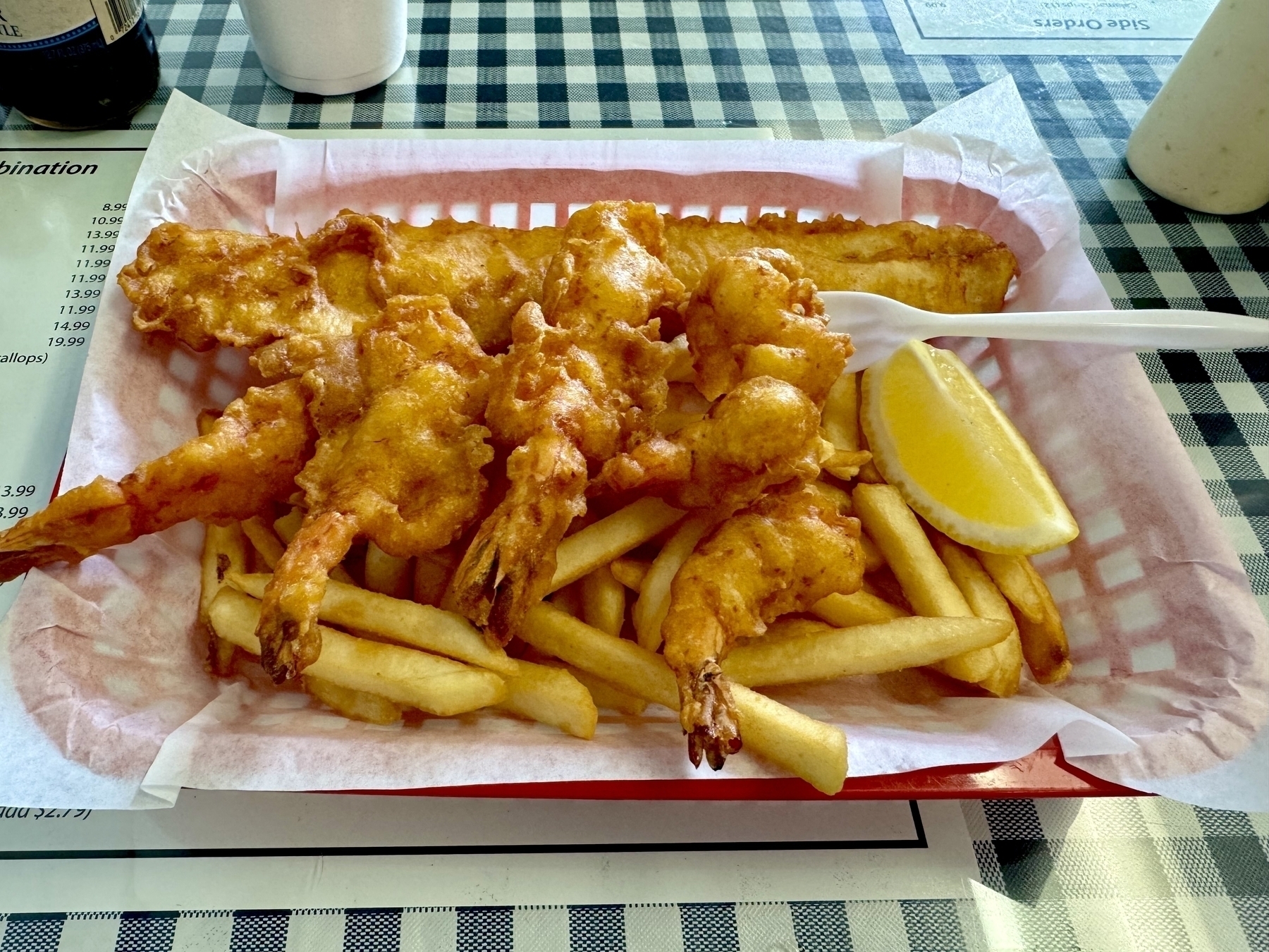 A basket of fish, prawns, and French fries.  
