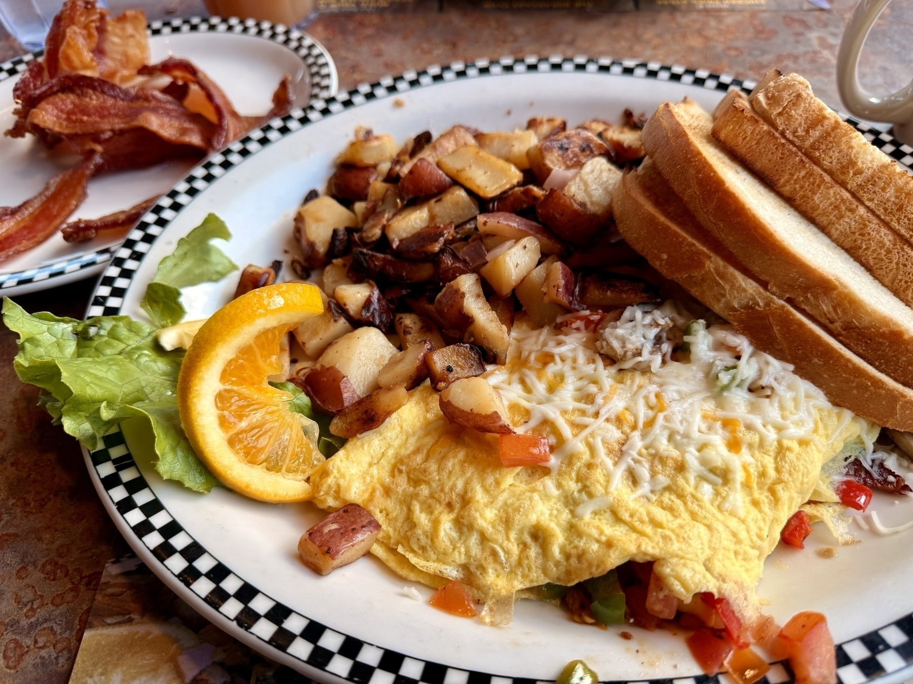 A plate of breakfast potatoes, veggie omelette, and toast. 