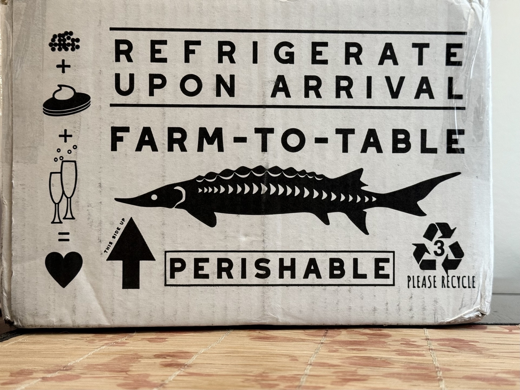 The outside of a cardboard box with graphics of a sturgeon and an infographic on how to pair caviar. 