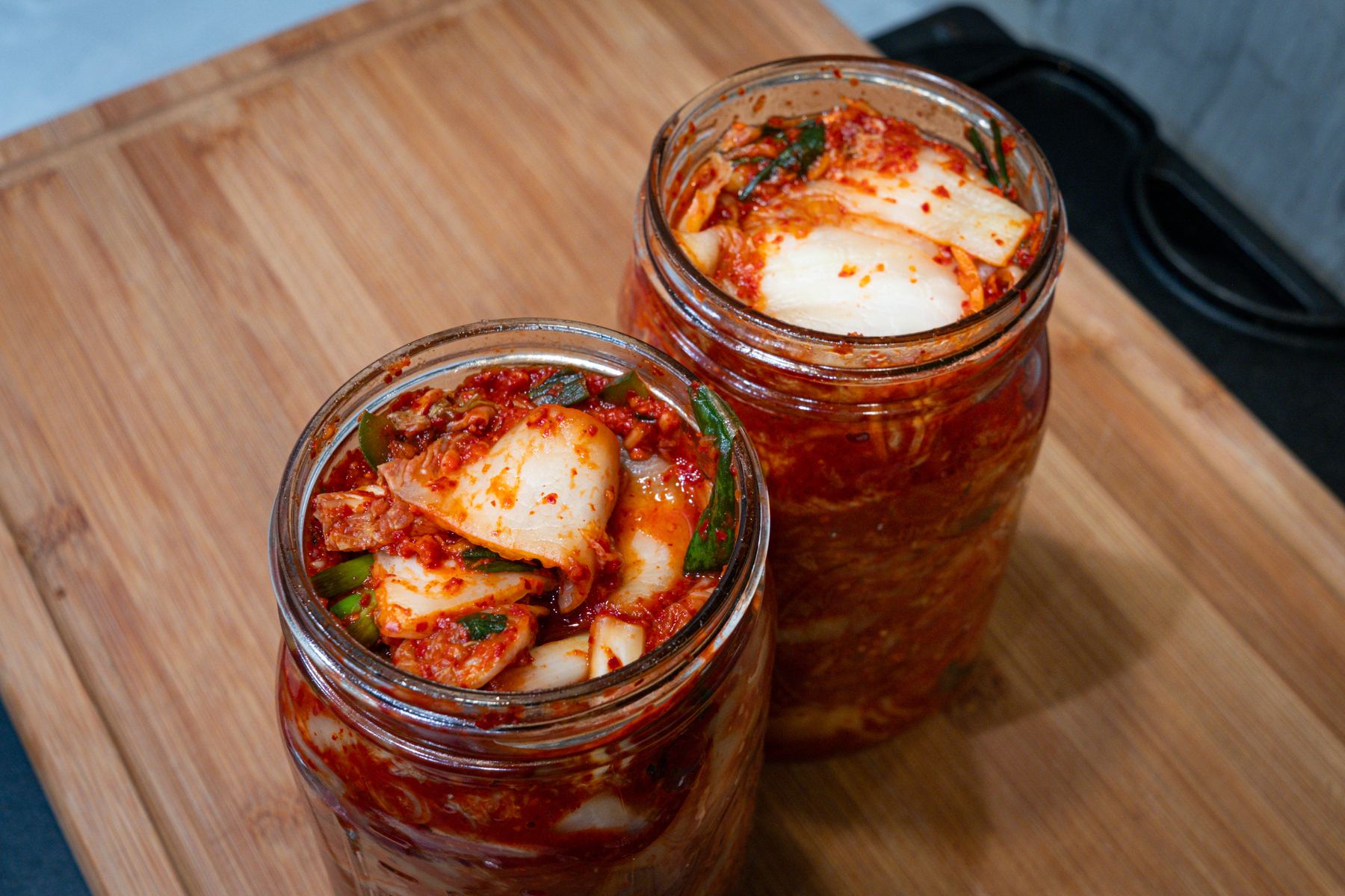 Two open mason jars of kimchi fermenting on its second day. 