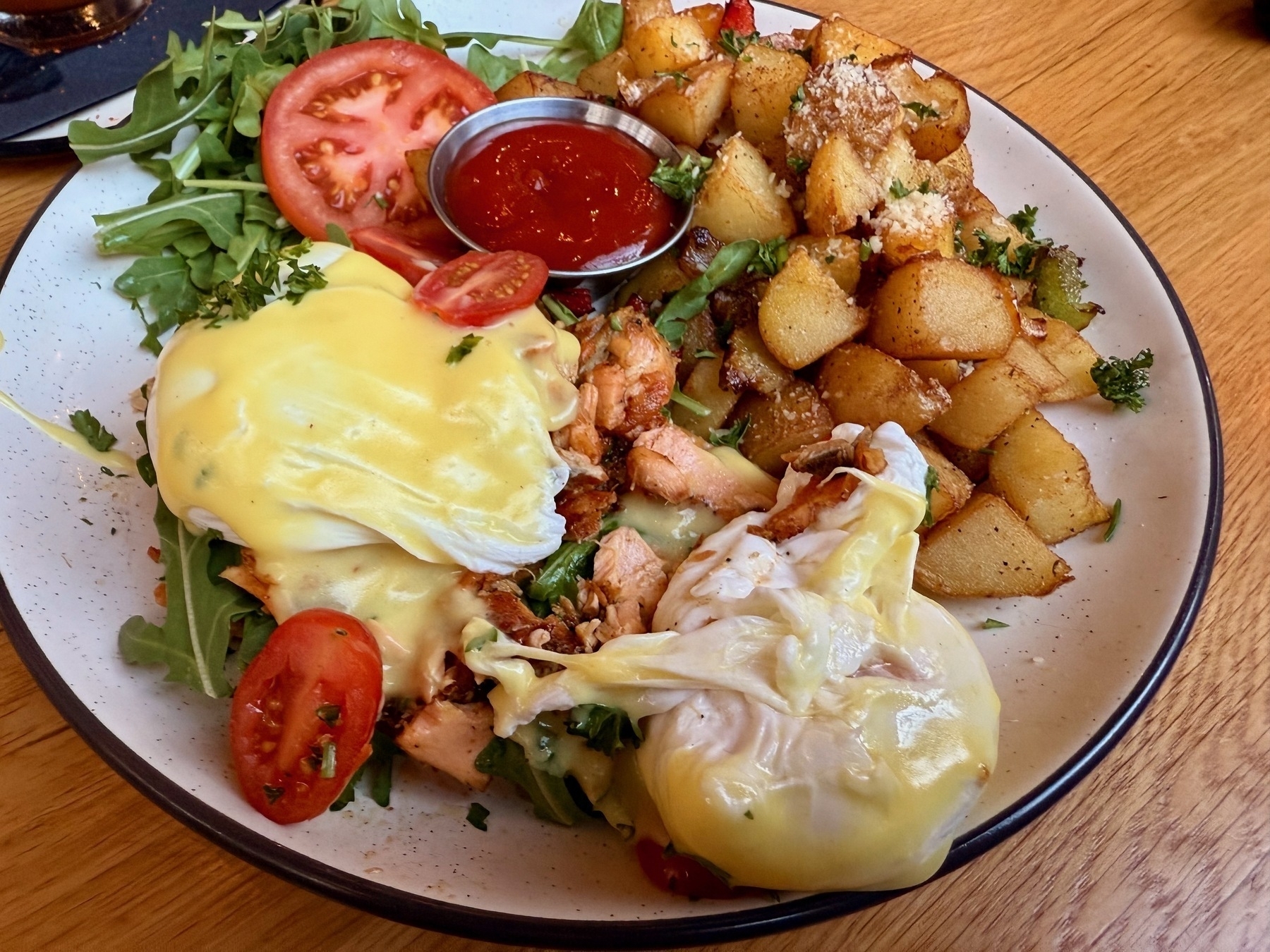 a plate of smoked salmon eggs benedict with country potatoes. 