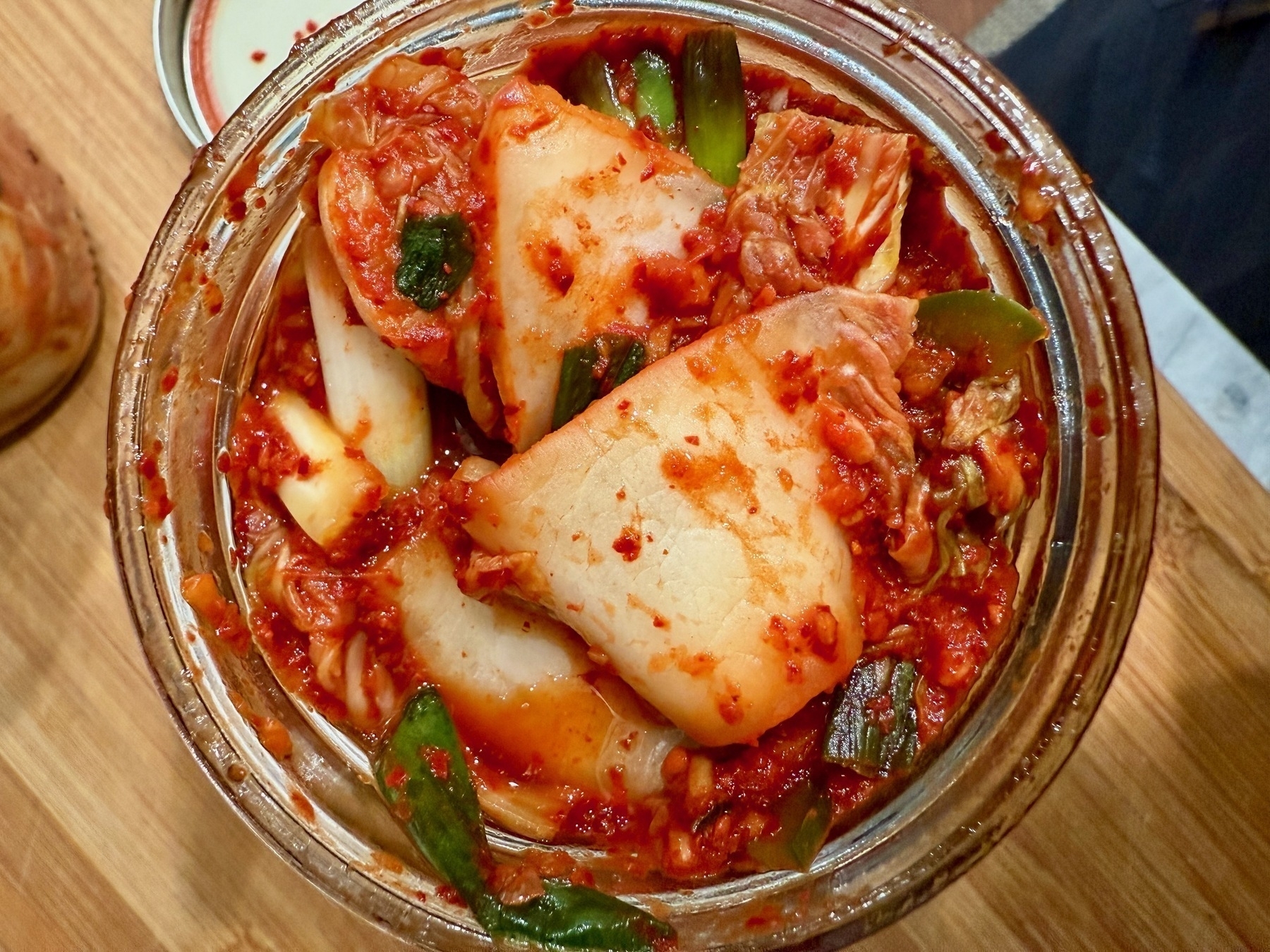 a top down view of day old kimchi in a mason jar. 