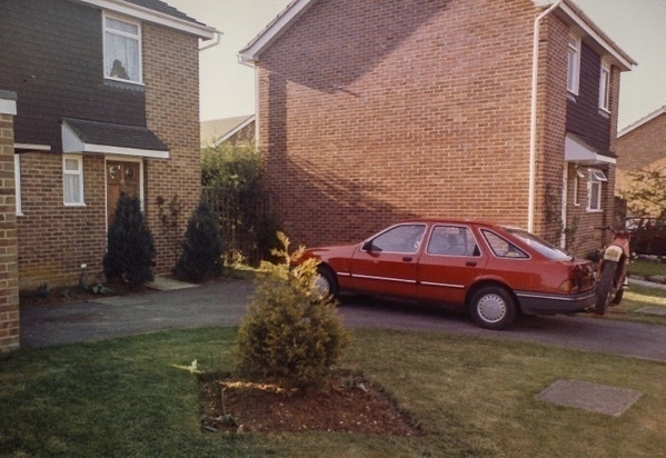 a photo of a red ford sierra car parked on a drive in 1985