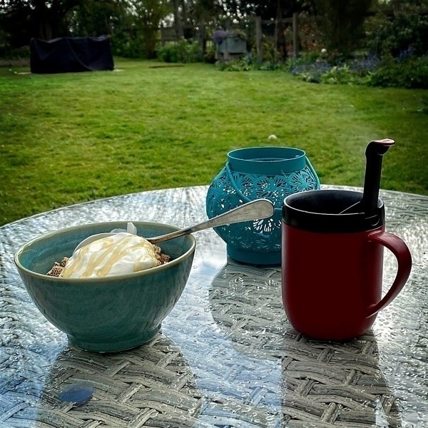 photo of a cereal bowl and coffee on a table in the garden