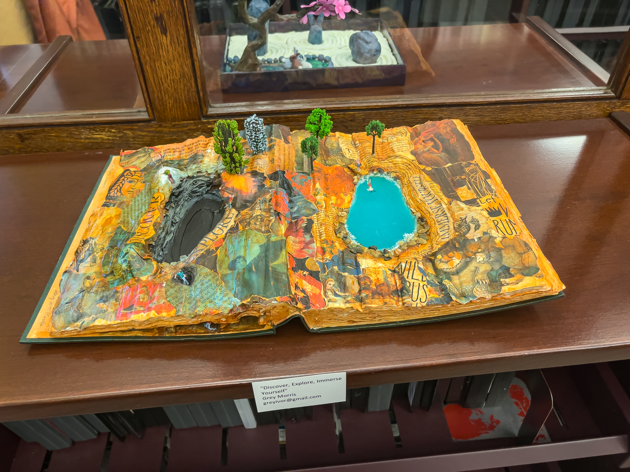 Sculpture of a landscape and two ponds made by carving out and adding to a book.